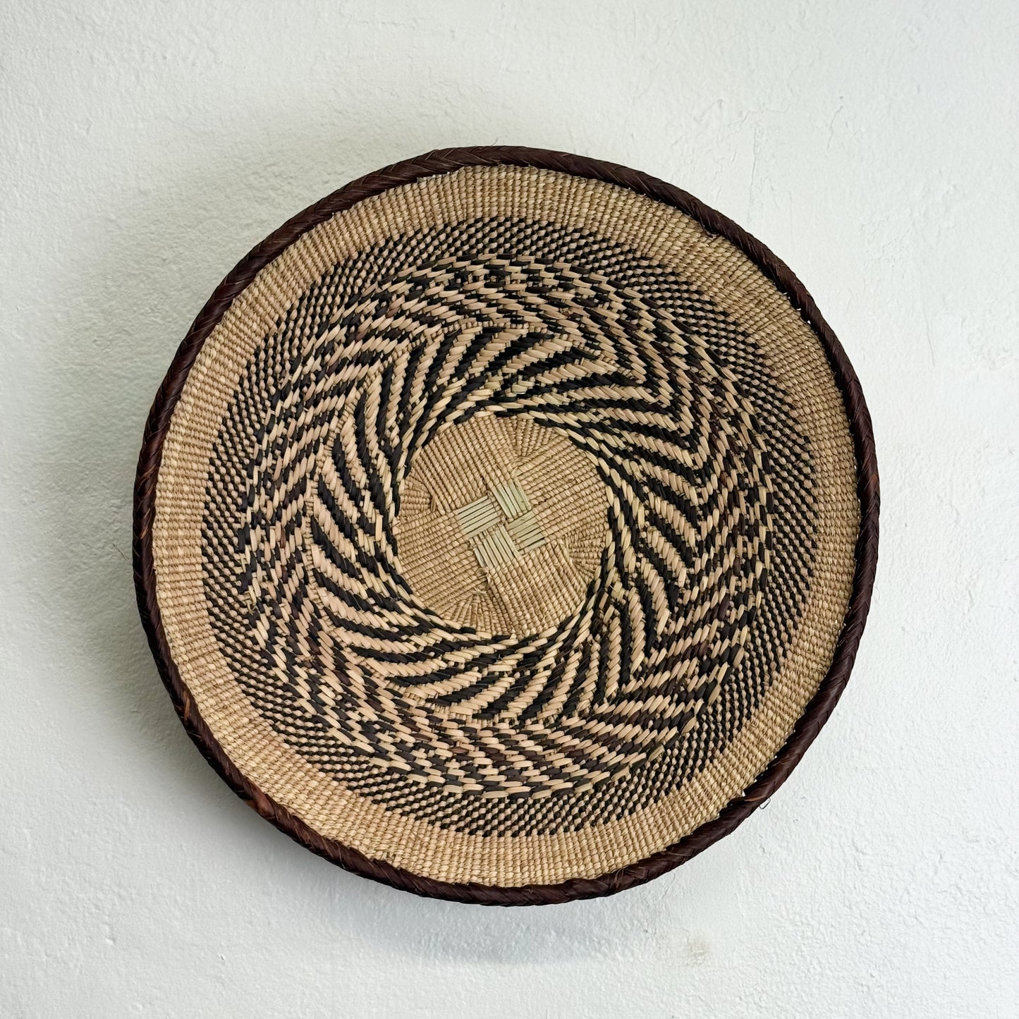 Round woven basket with a concentric pattern on a white background