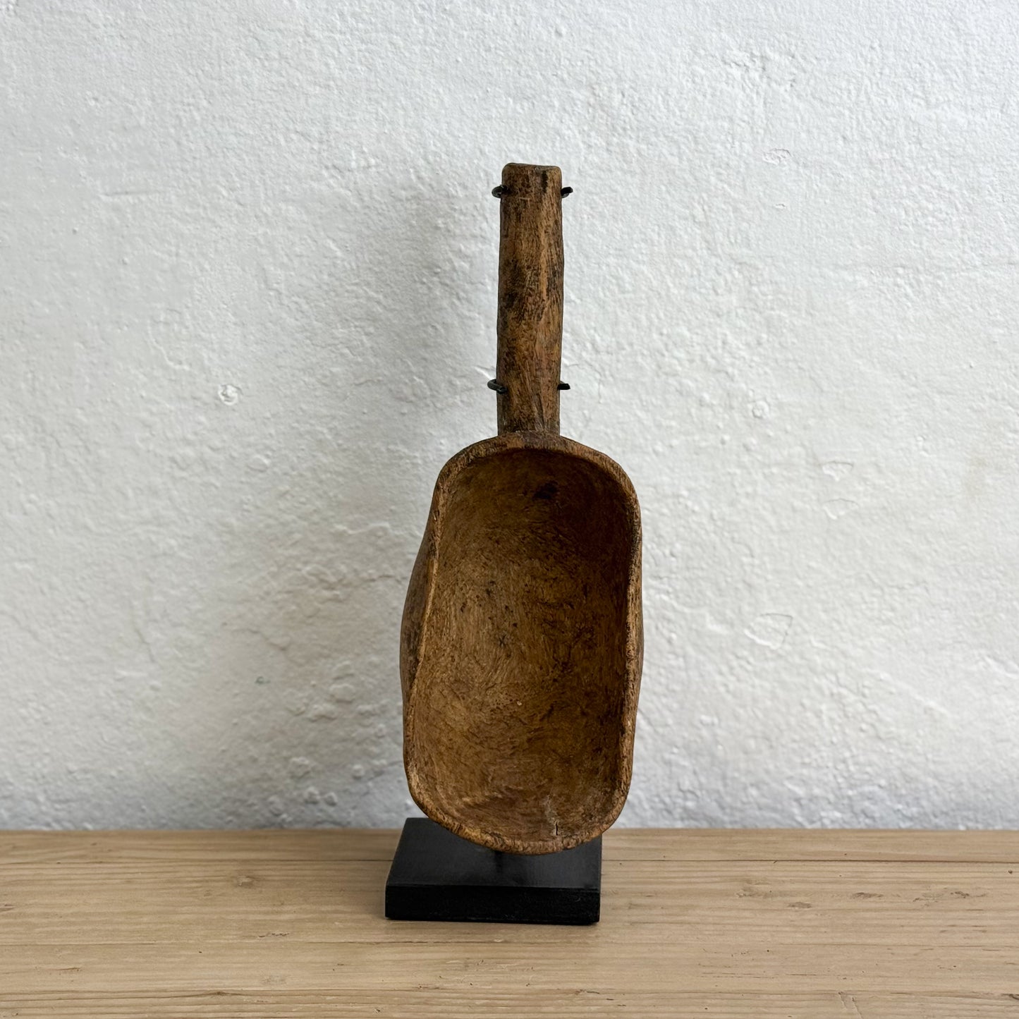 Vintage brown scoop on a stand against a white wall