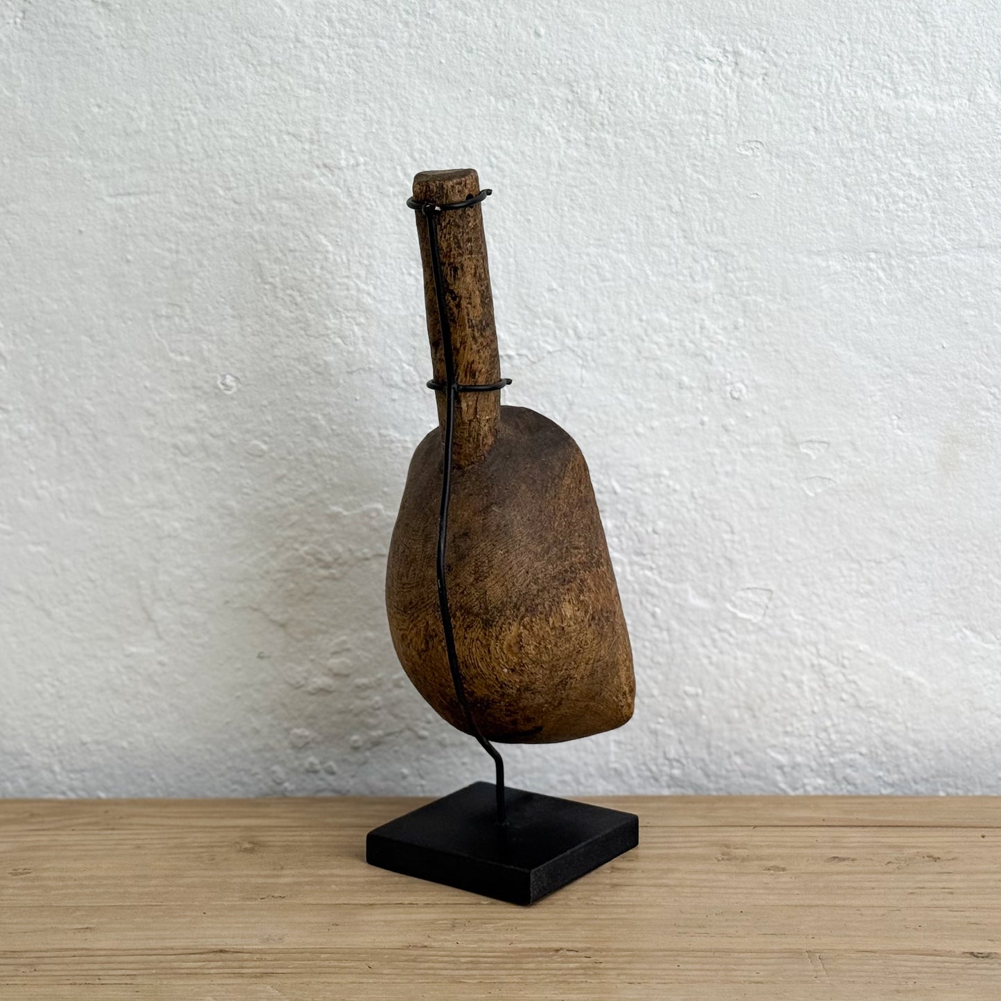 Vintage wooden cowbell on a stand against a white wall