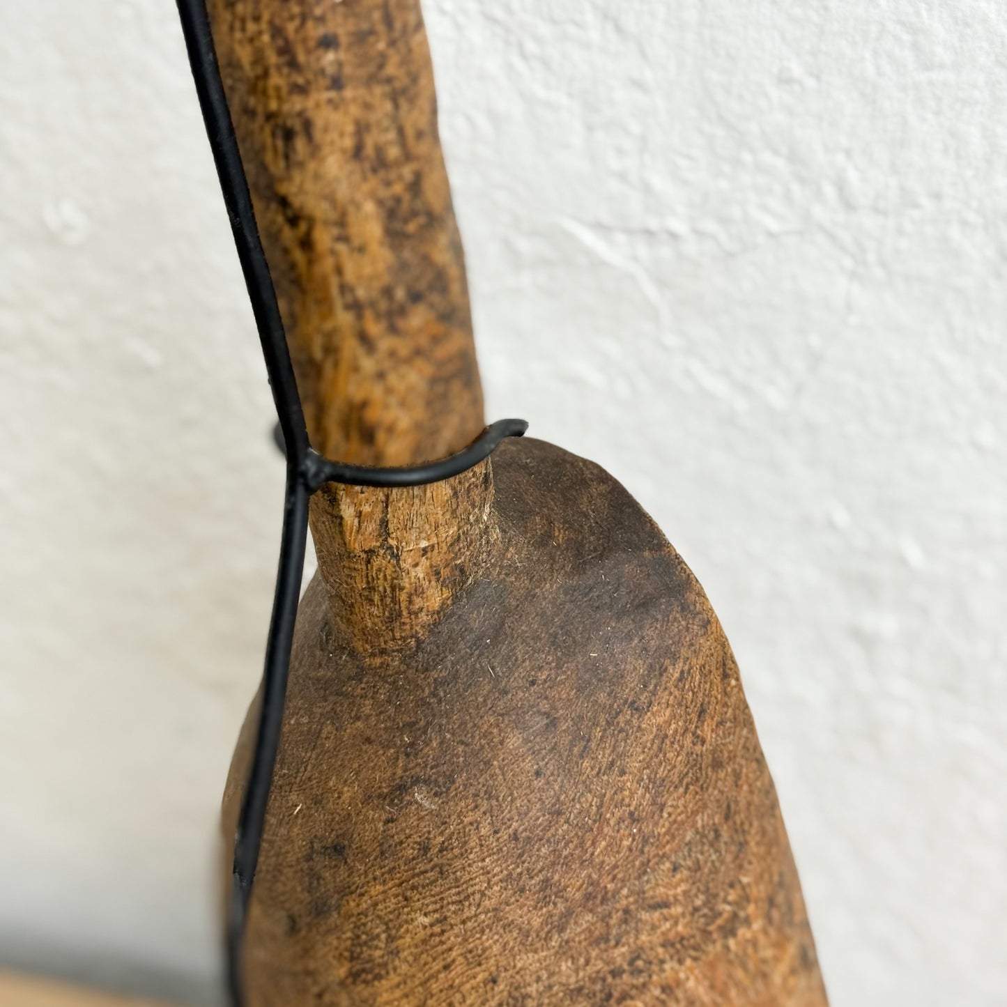 Close-up of a wooden tool with a black strap on a white background