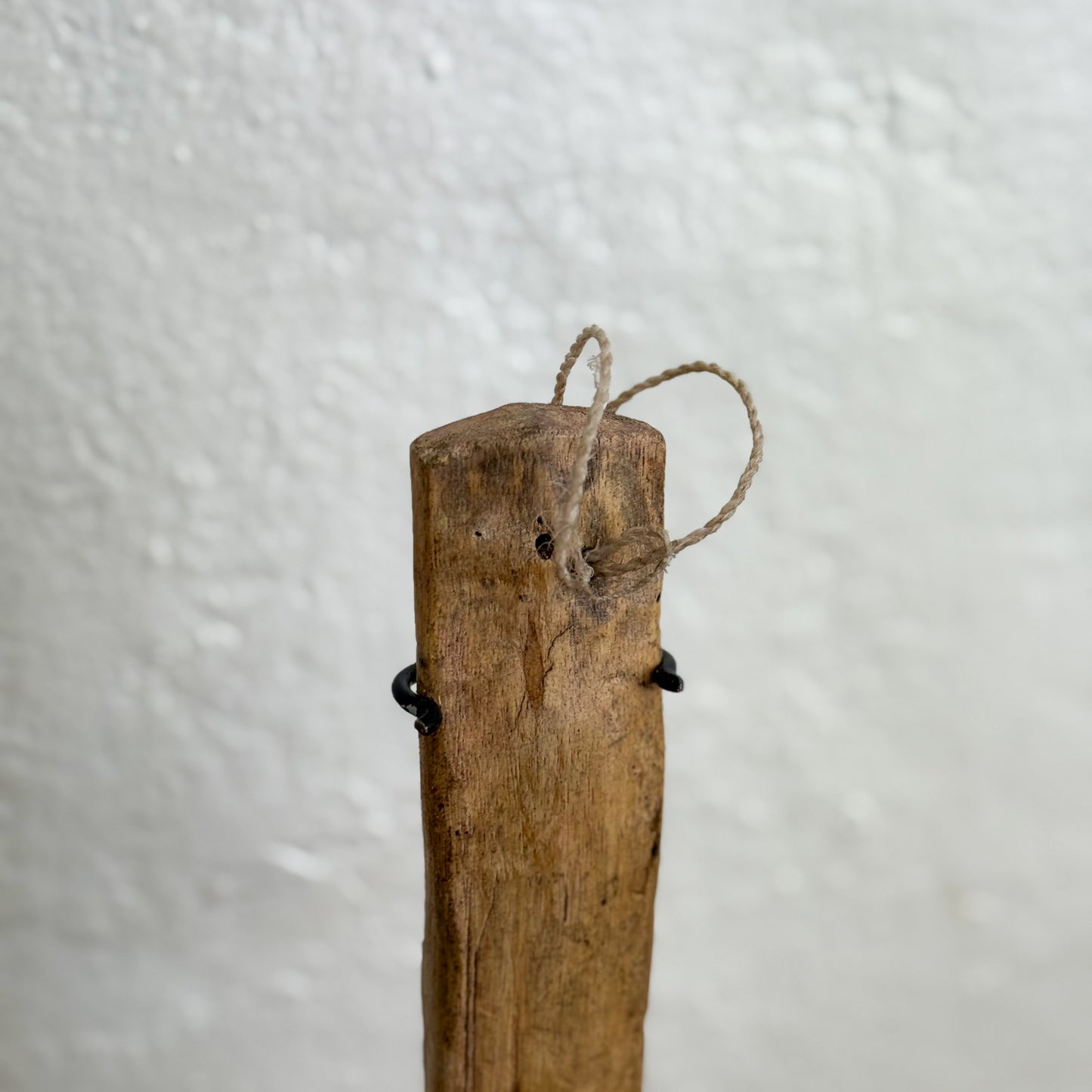 Wooden post with twine tied to it against a white background