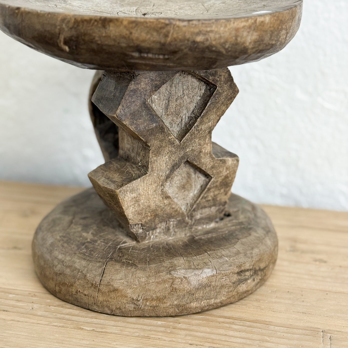 Wooden pedestal with geometric design on a wooden surface
