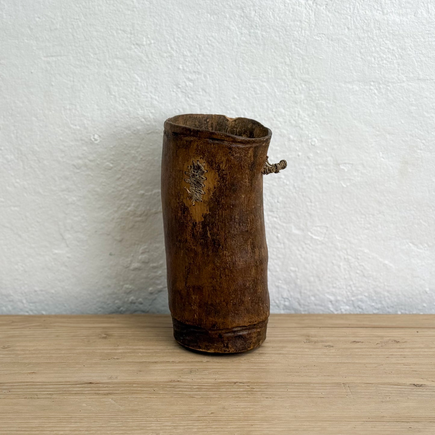 Vintage wooden container on a light wood surface with a white textured wall background