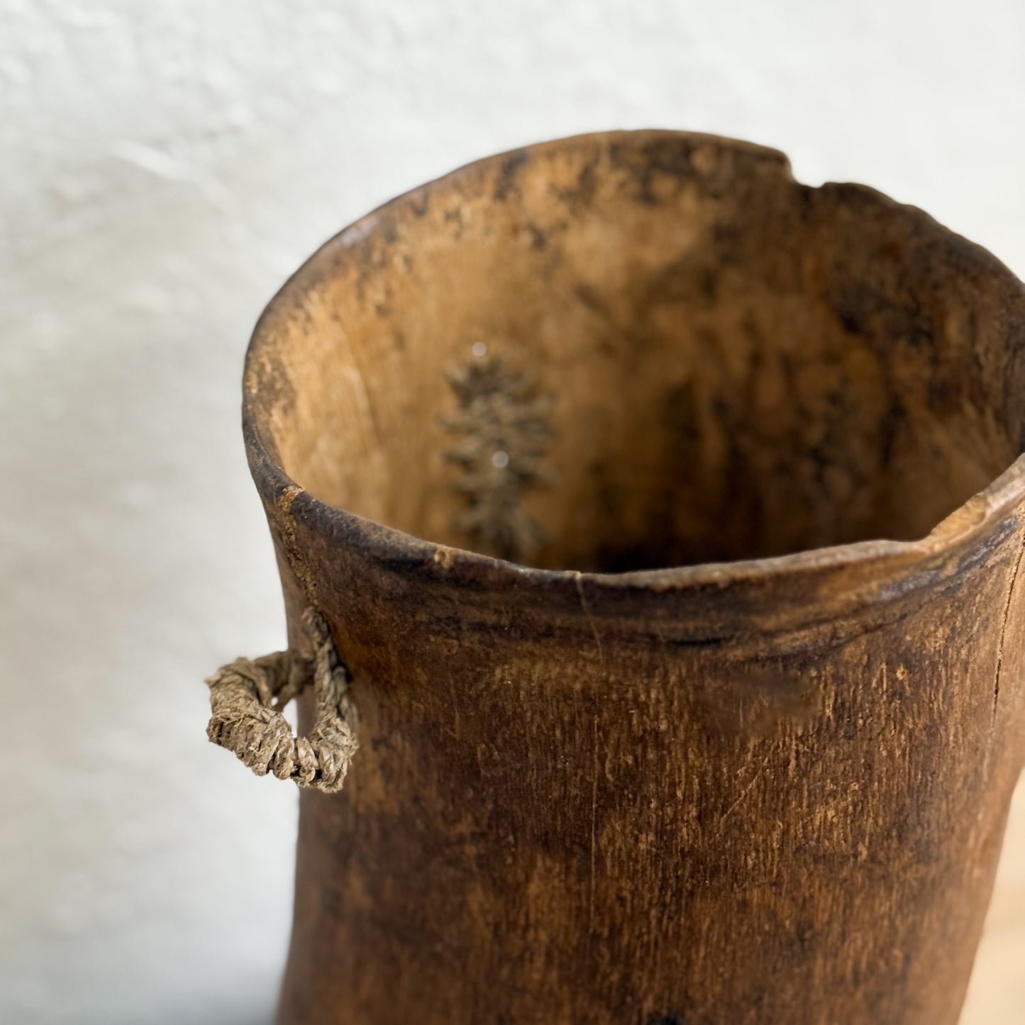 Close-up of a wooden vase with a textured surface on a light background