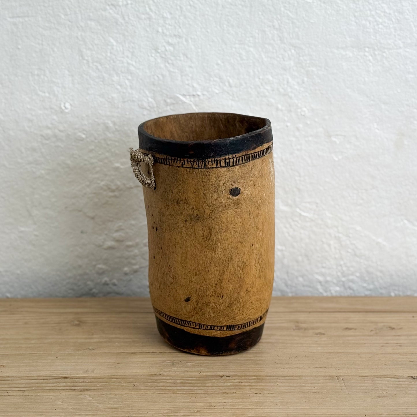 Wooden cup with a textured surface on a wooden surface and white background