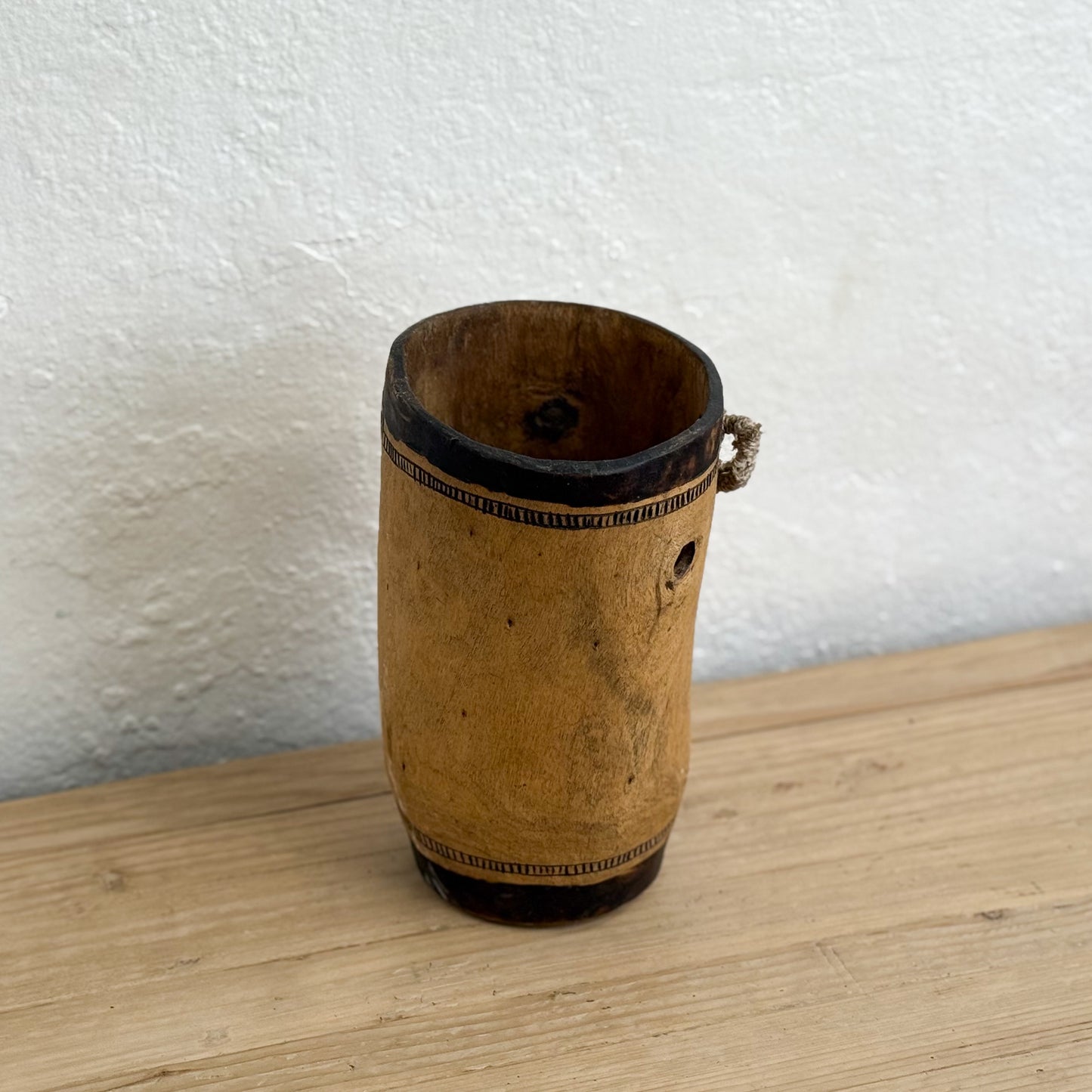 Wooden vase with decorative patterns on a wooden surface