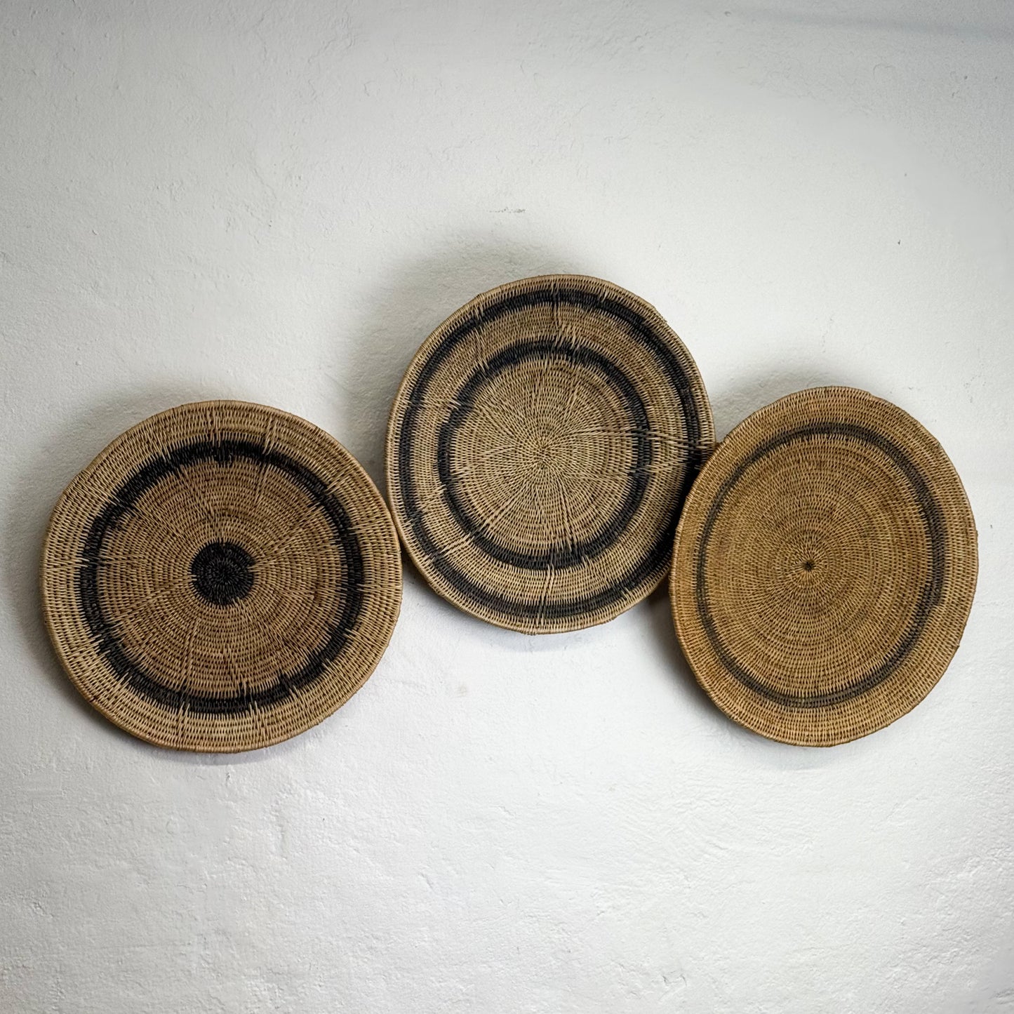 Three woven baskets with concentric circle patterns on a white background