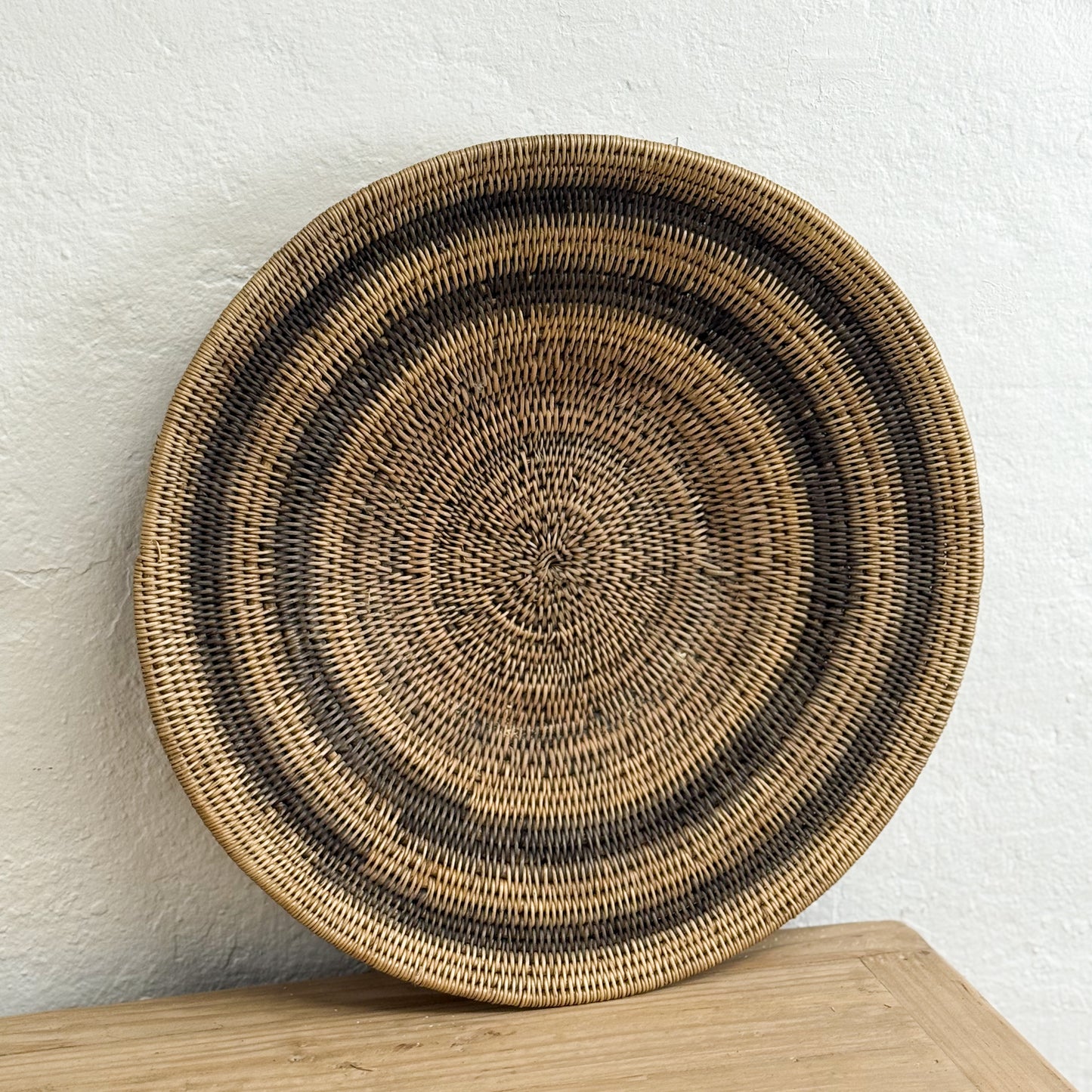Woven basket with concentric circle pattern on a wooden surface