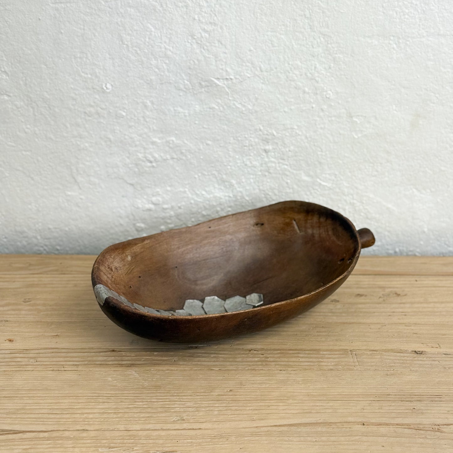 Wooden bowl with stones on a wooden surface and white wall background