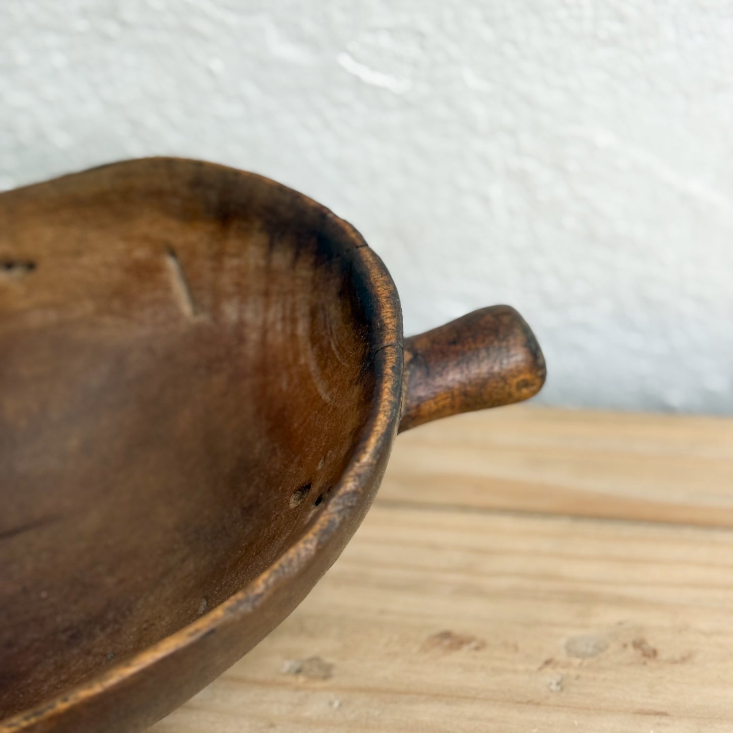 Wooden bowl with a handle on a wooden surface