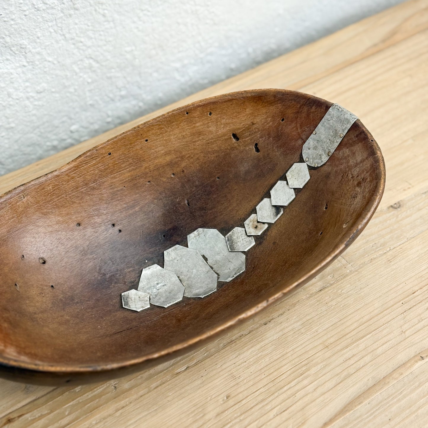 Wooden spoon with geometric stone inlays on a wooden surface