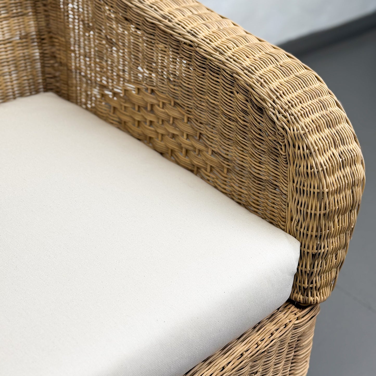 Wicker chair with white cushion on a gray background