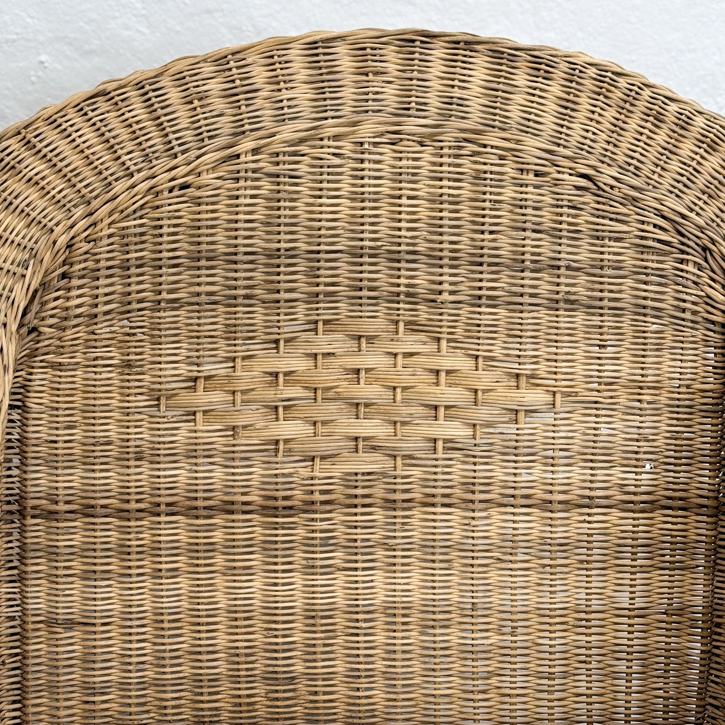 Close-up of a woven wicker chair seat against a neutral background