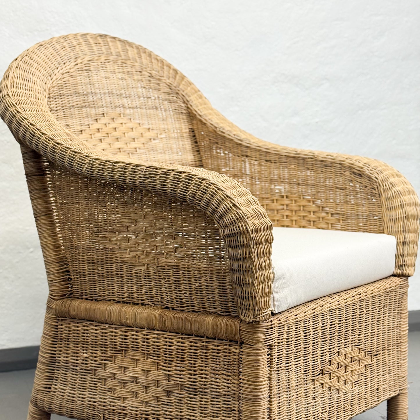 Wicker chair with a white cushion on a light gray background