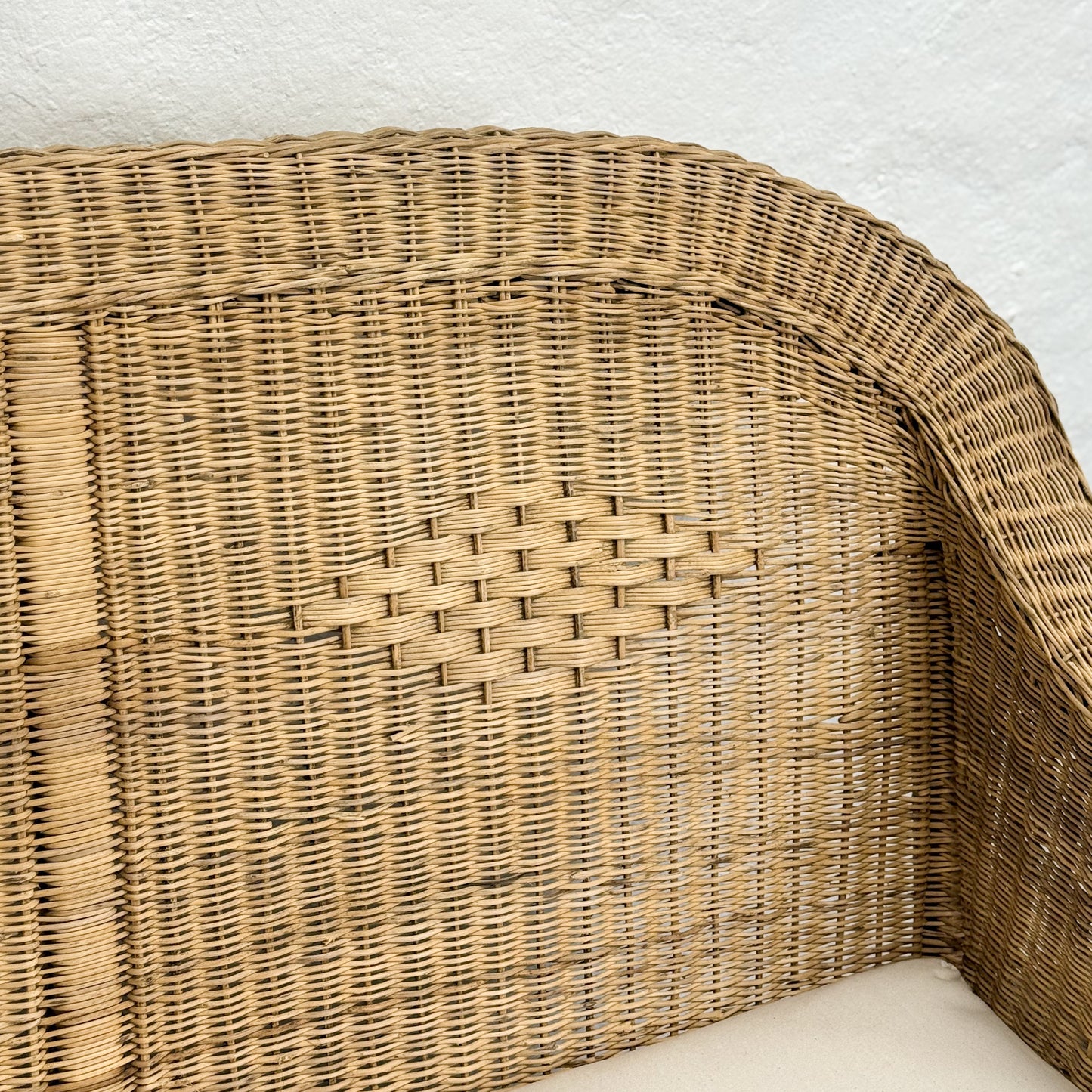 Close-up of a wicker chair corner with a textured white background