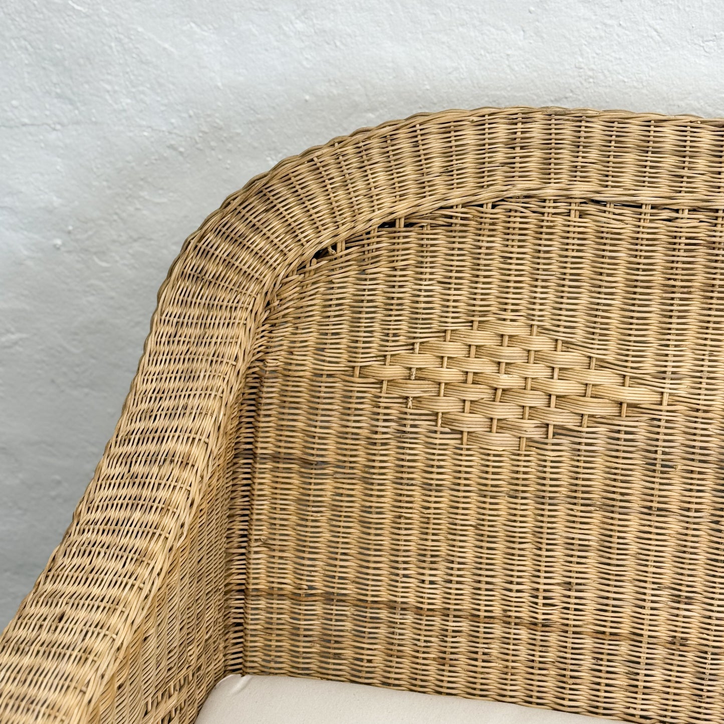 Close-up of a wicker chair corner with a plain background