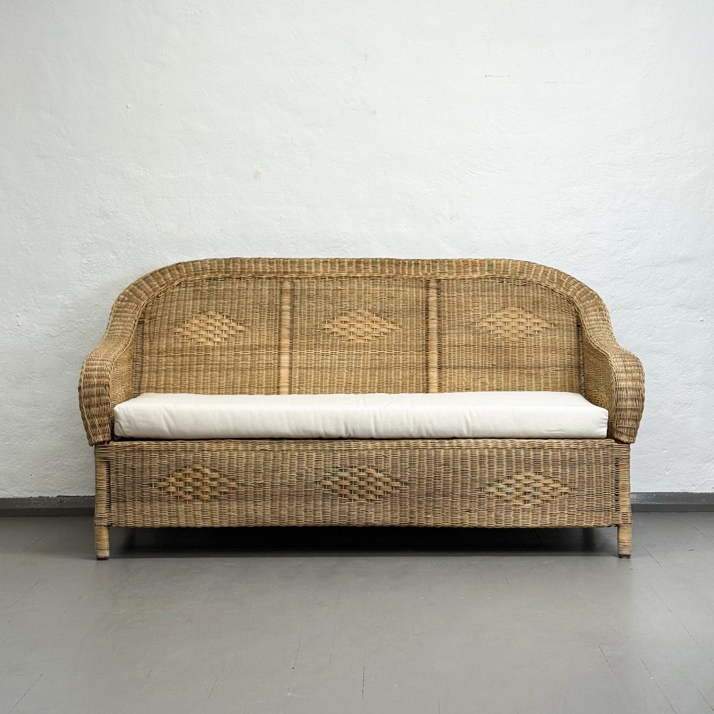 Wicker sofa with a white cushion on a plain background