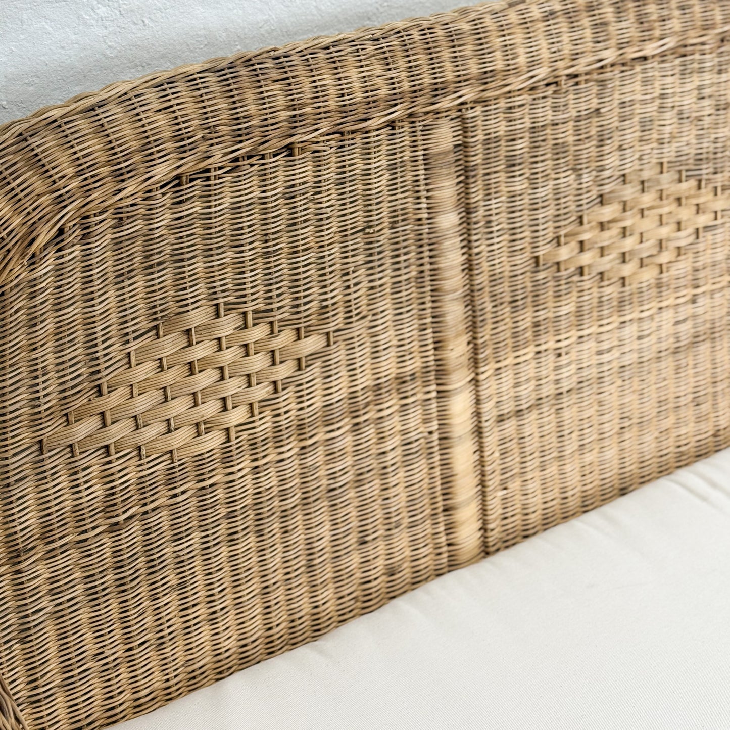 Wicker headboard on a bed with white bedding