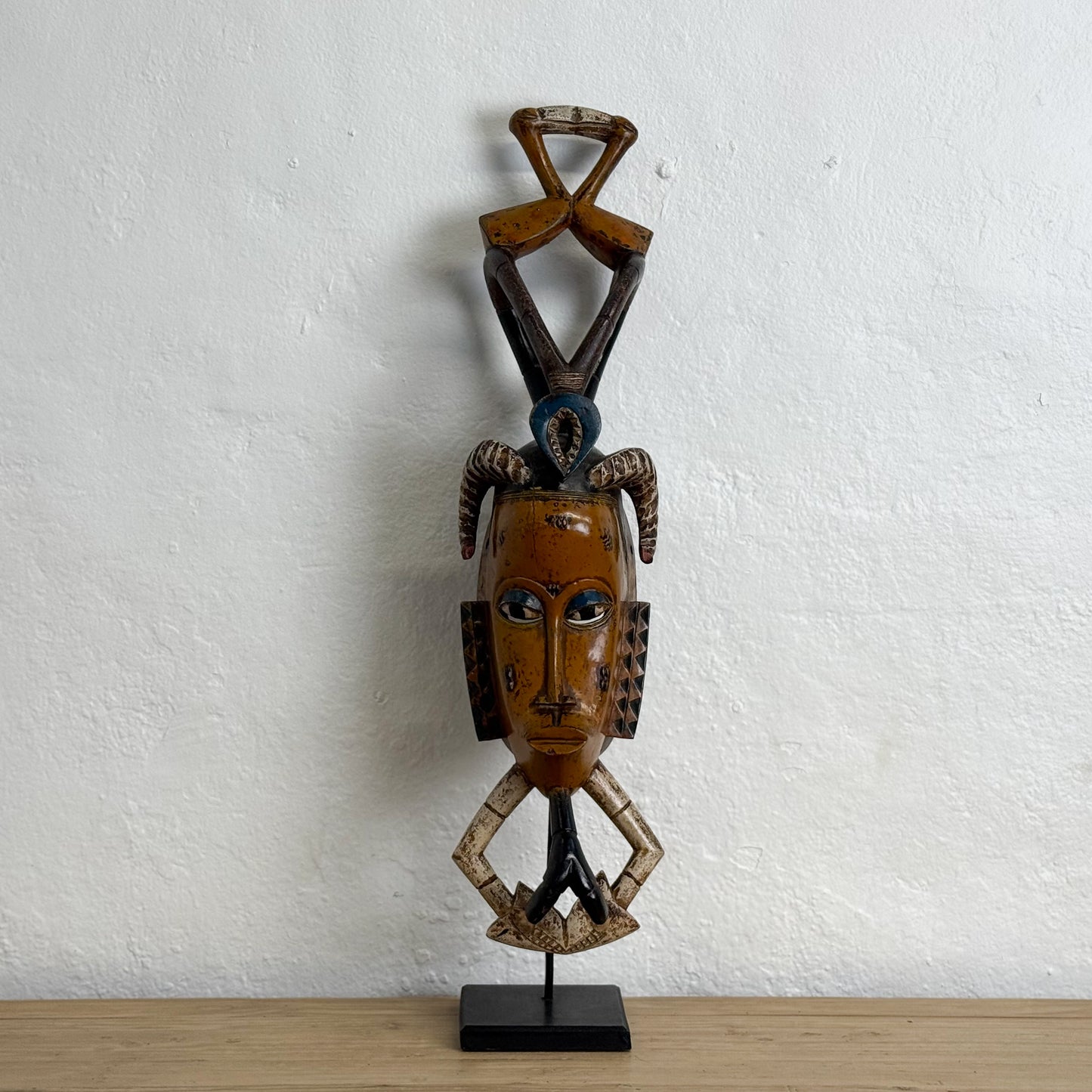 African mask on a stand against a white wall