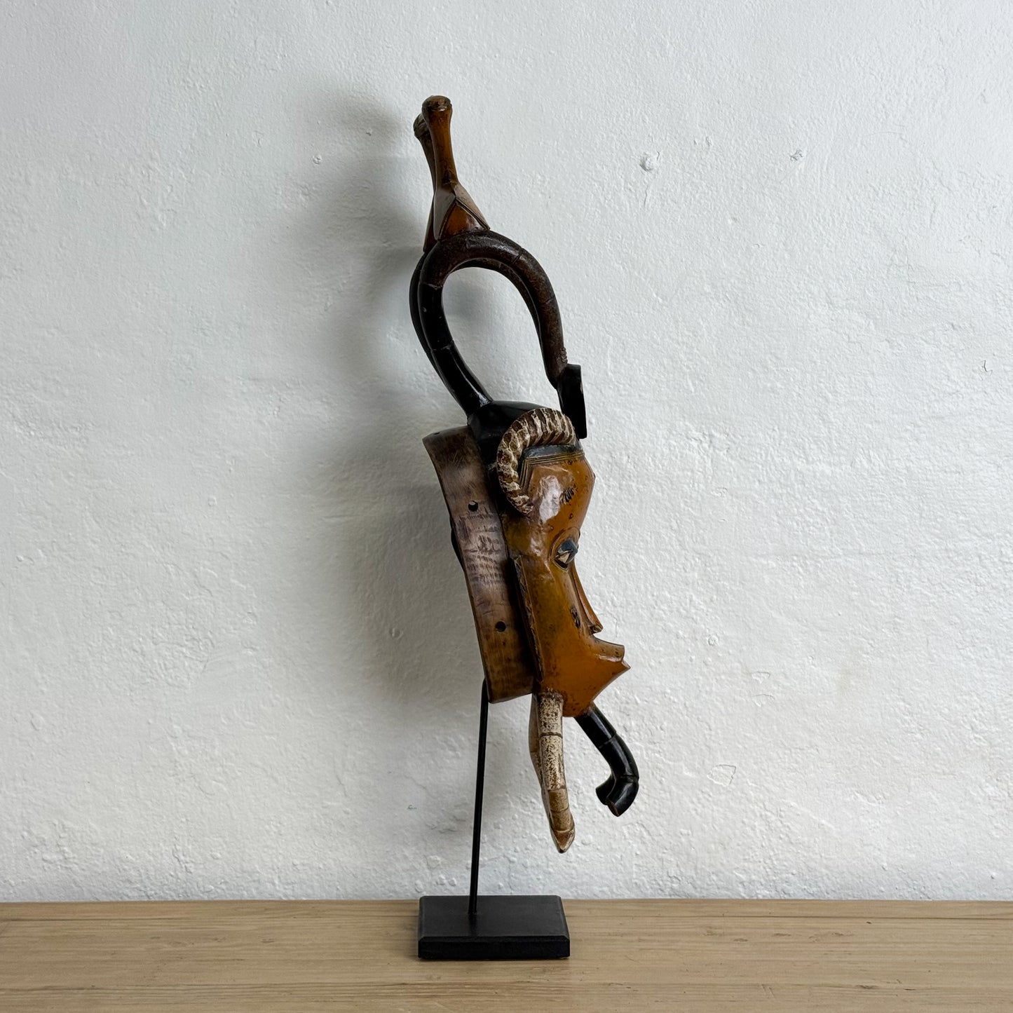 Decorative wall hook with a unique design on a stand against a white wall.