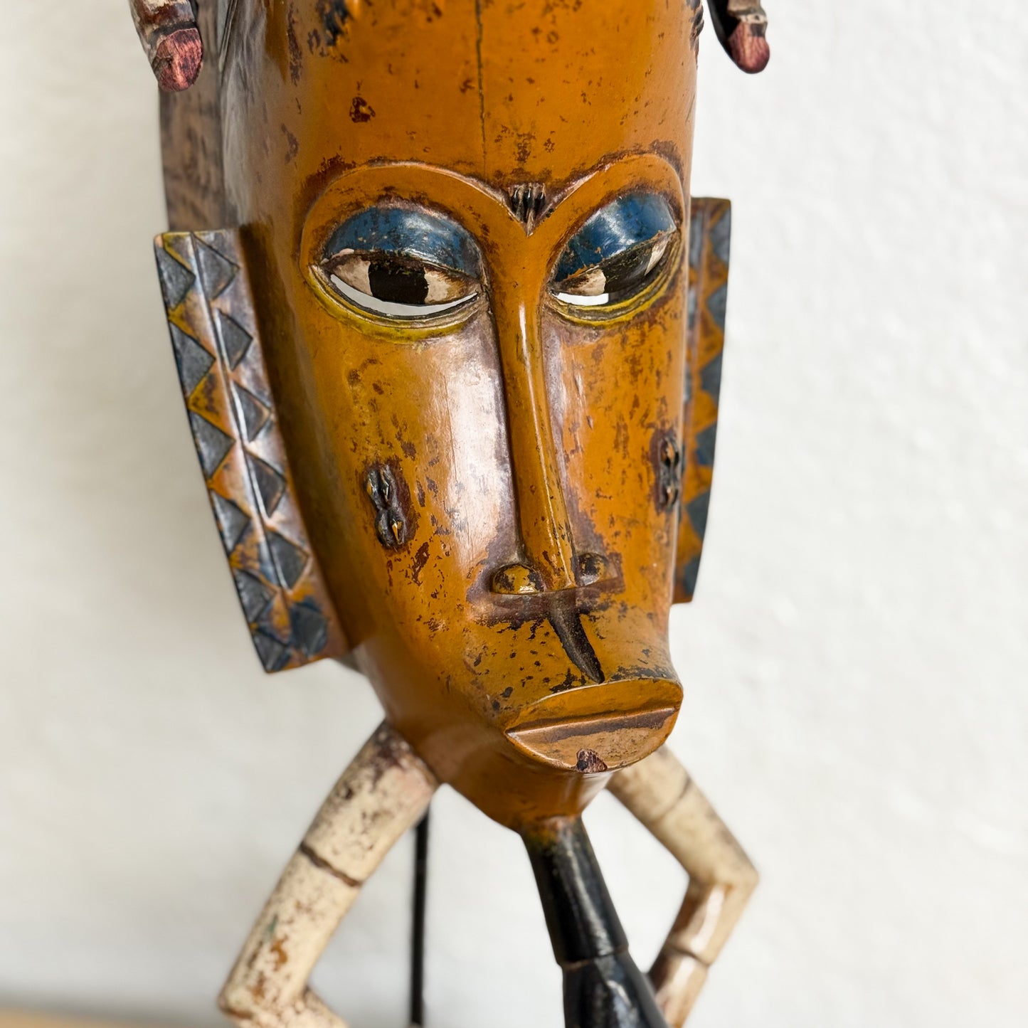 Wooden mask with blue eyes and decorative patterns on a white background