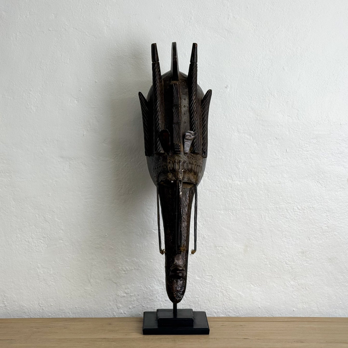 Decorative mask on a stand against a white wall