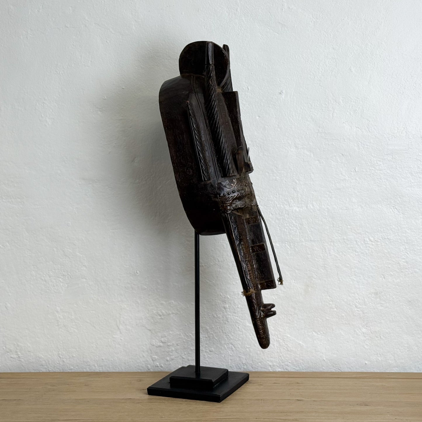 Wooden sculpture on a stand against a white wall