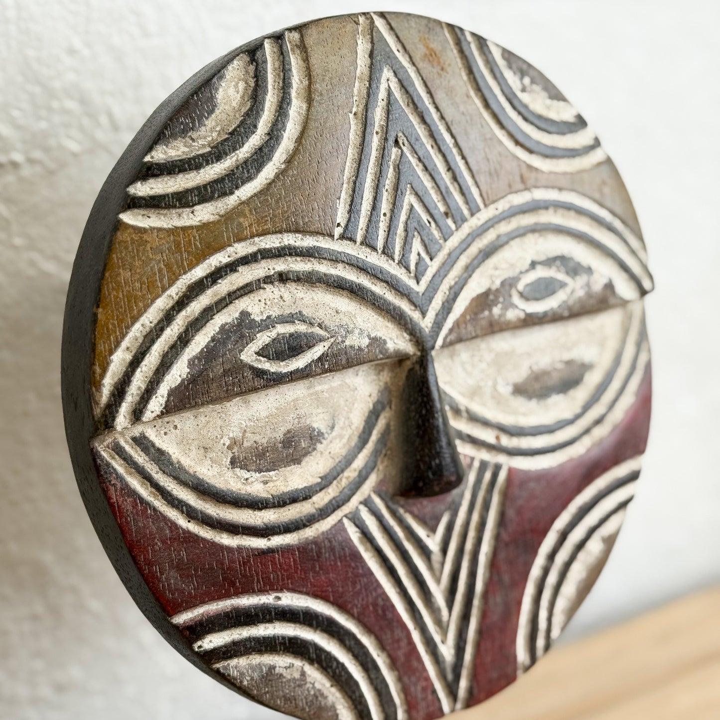 Close-up of a wooden mask with intricate carvings on a neutral background