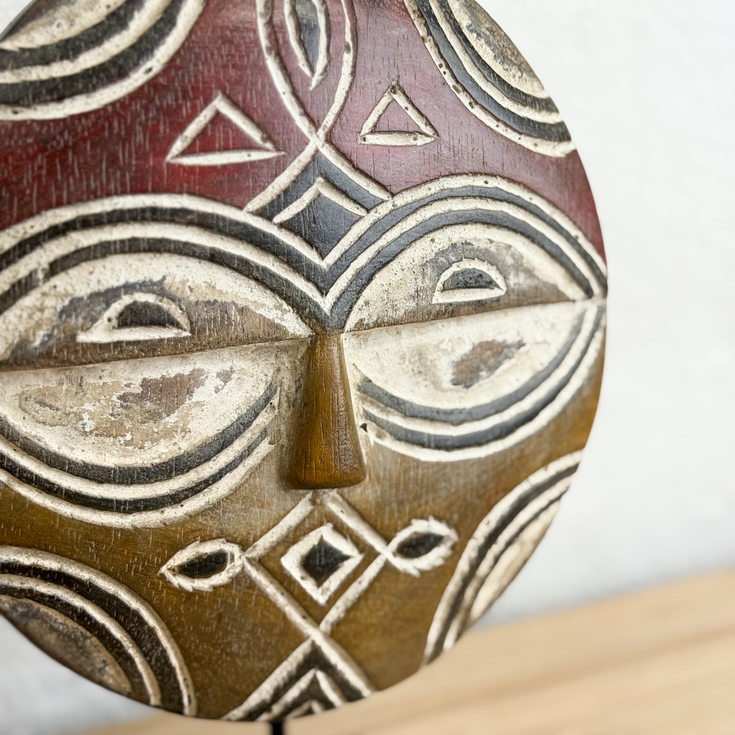 Close-up of a wooden mask with geometric patterns on a white background