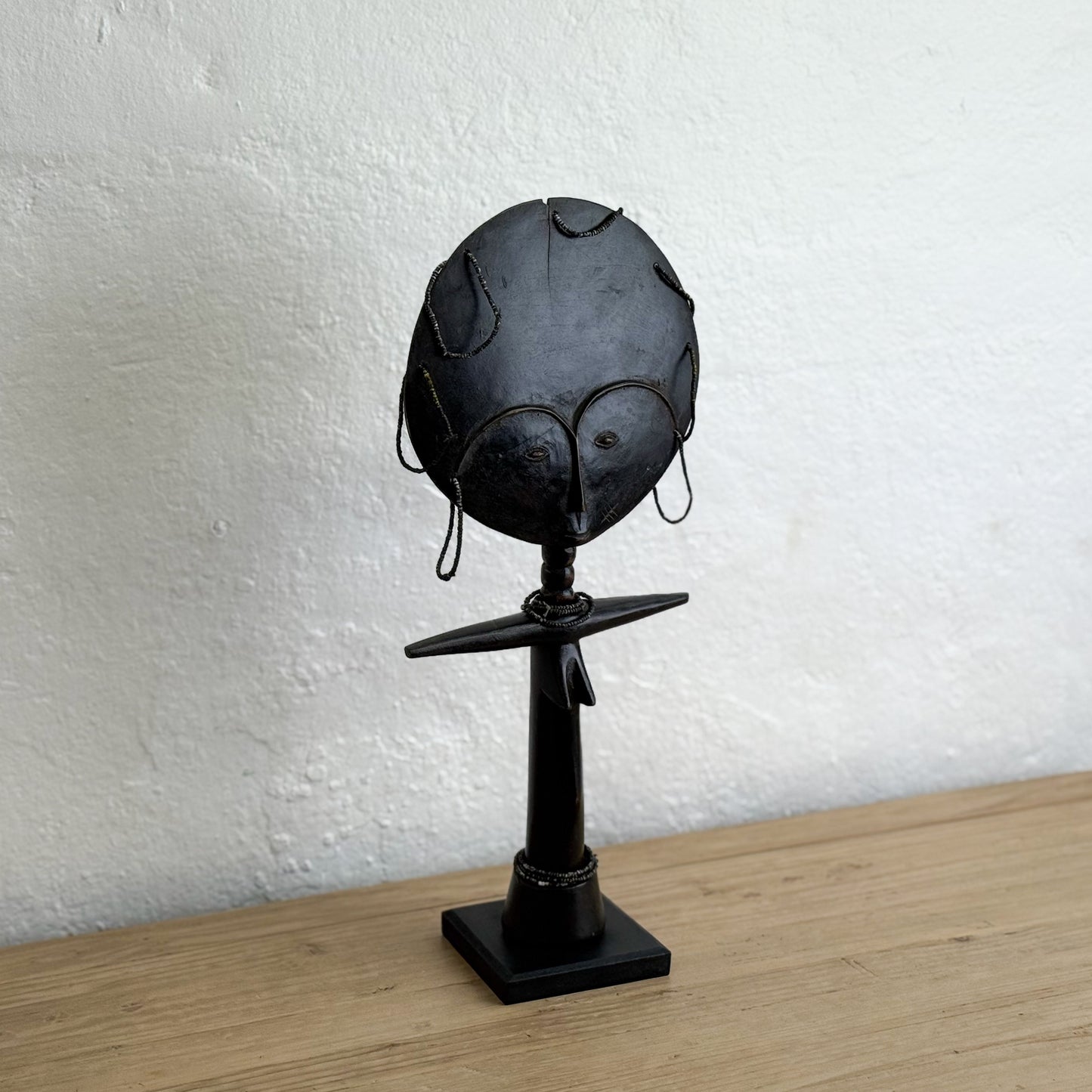 Black helmet on a stand against a white wall