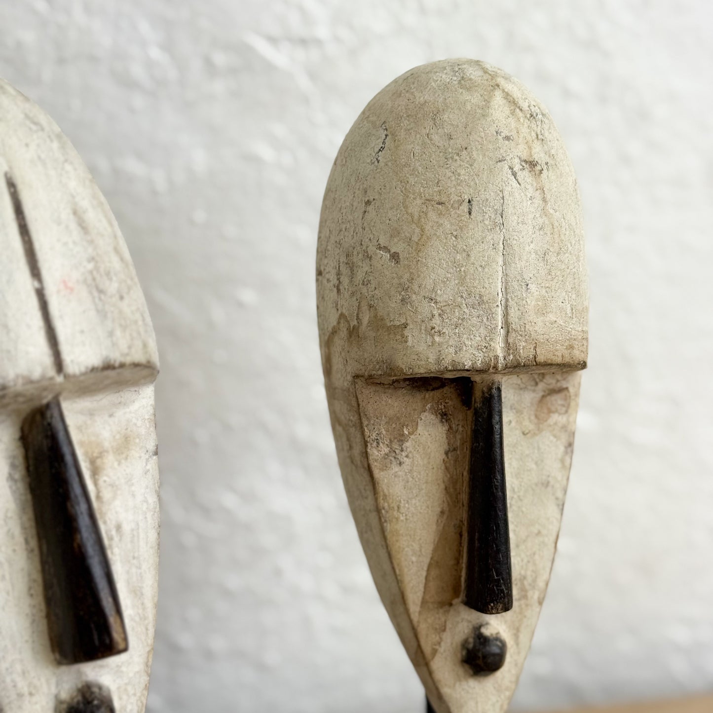 Two stone-like masks with black accents on a textured white background