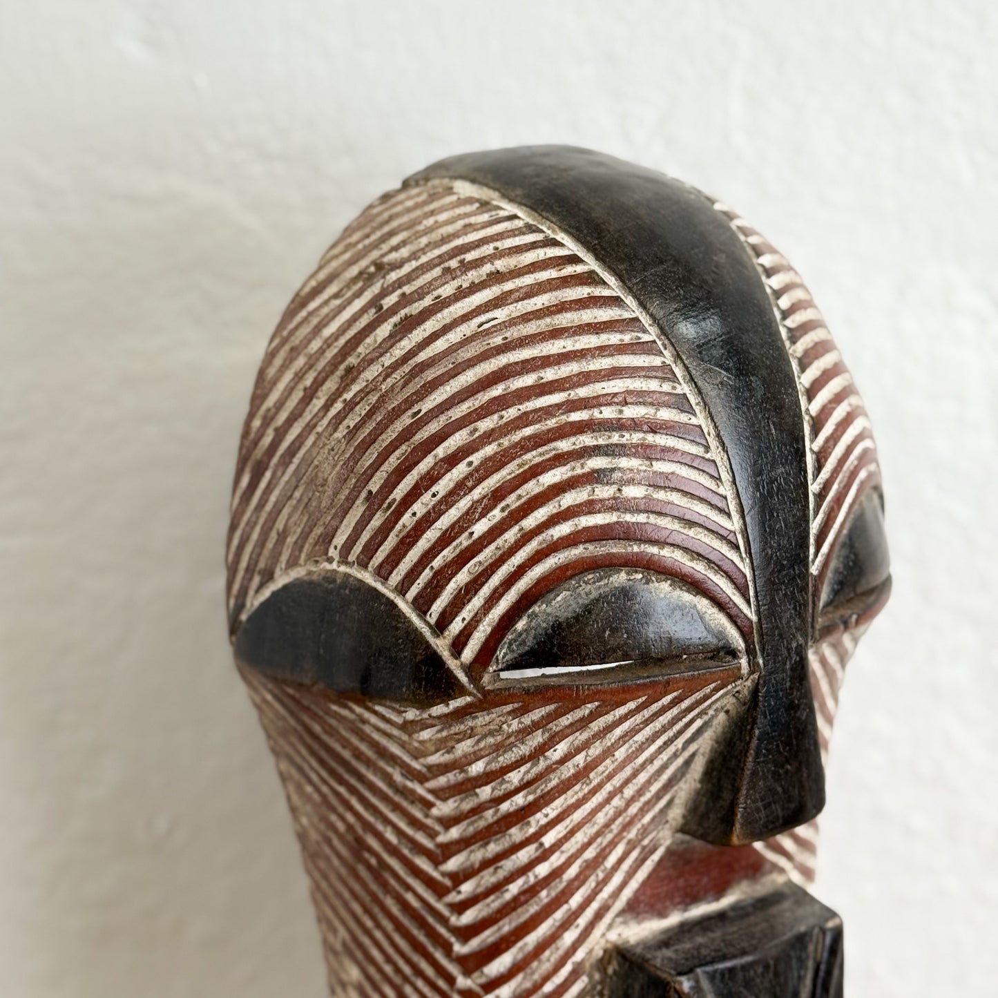 Close-up of a wooden mask with intricate carvings on a white background