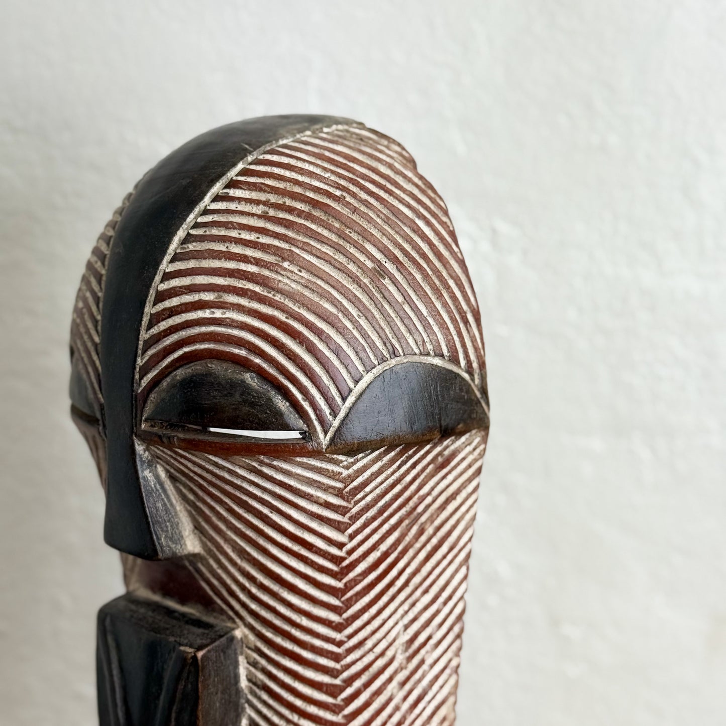Wooden mask with intricate patterns on a plain background