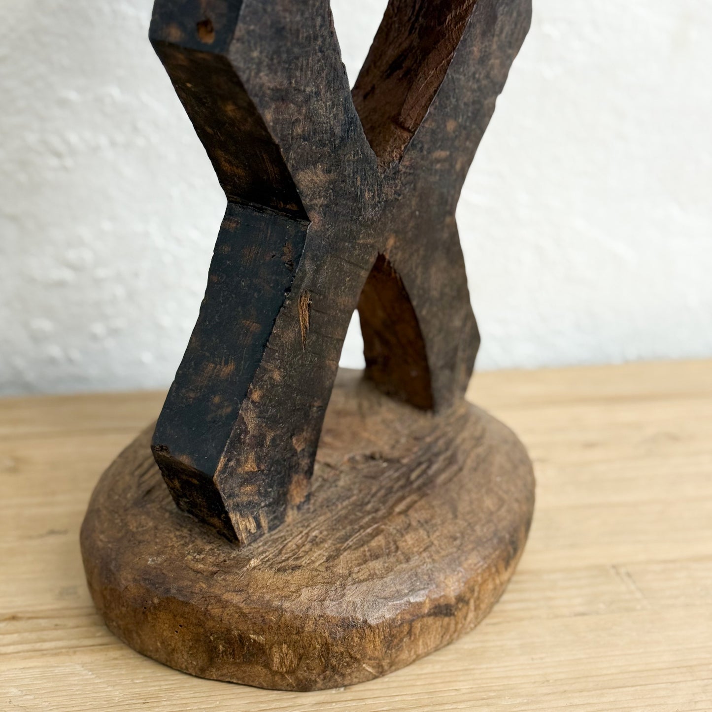 Wooden sculpture on a wooden base with a white textured background