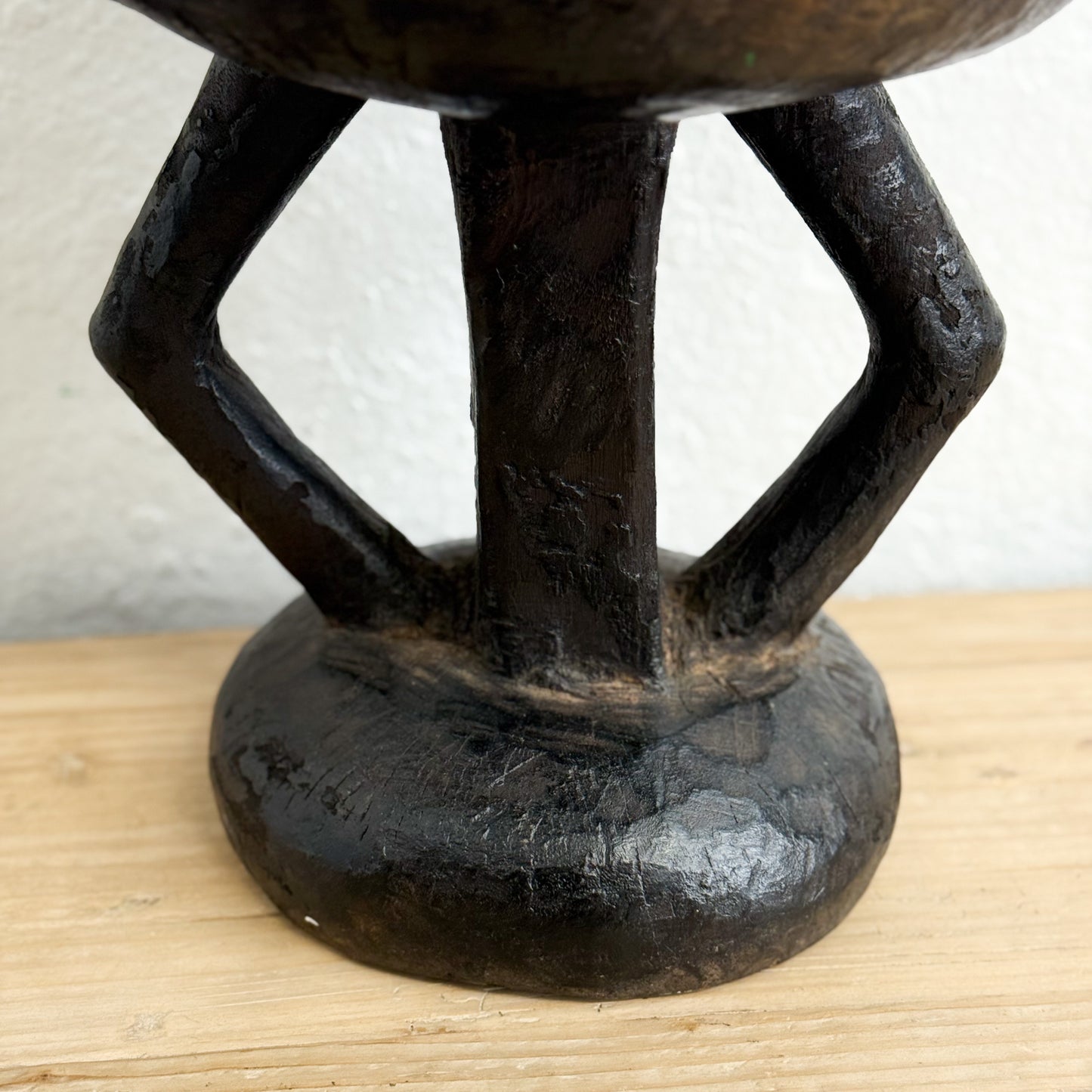 Black metal stool with a textured surface on a wooden surface