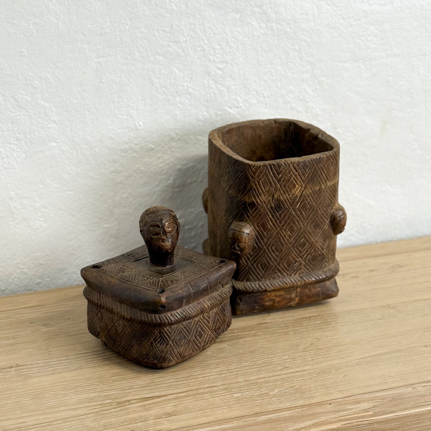Two wooden containers with intricate carvings on a light wood surface.
