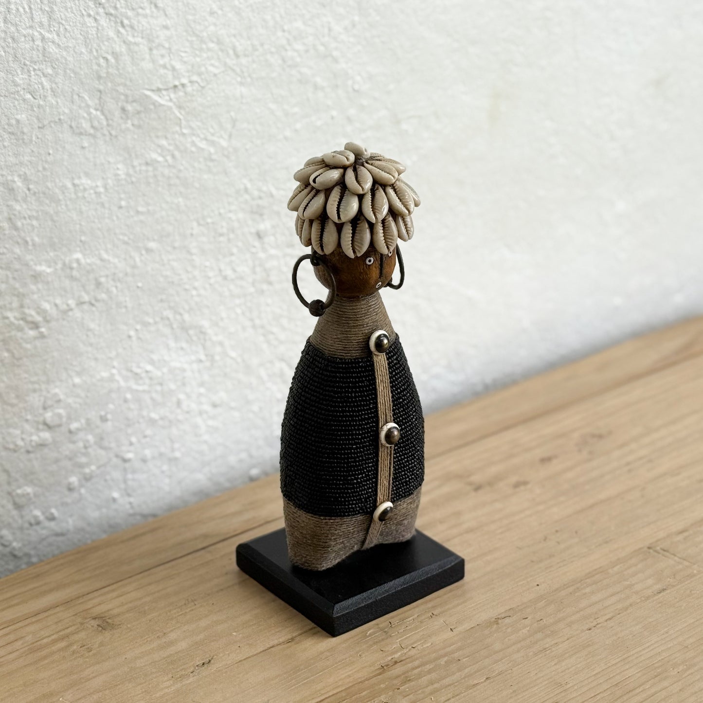 Textured figurine on a wooden surface with a white wall background