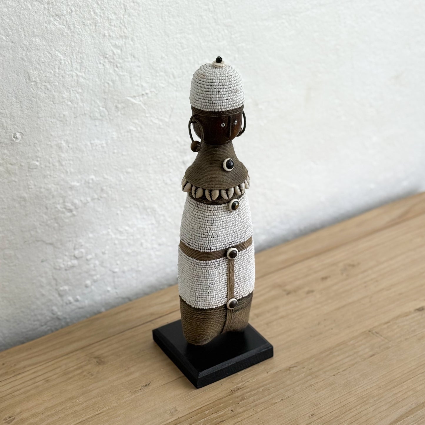 Decorative figure on a stand against a white wall