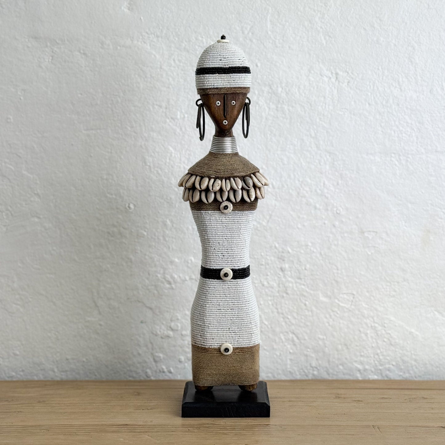 Decorative figure on a wooden surface with a white textured wall background