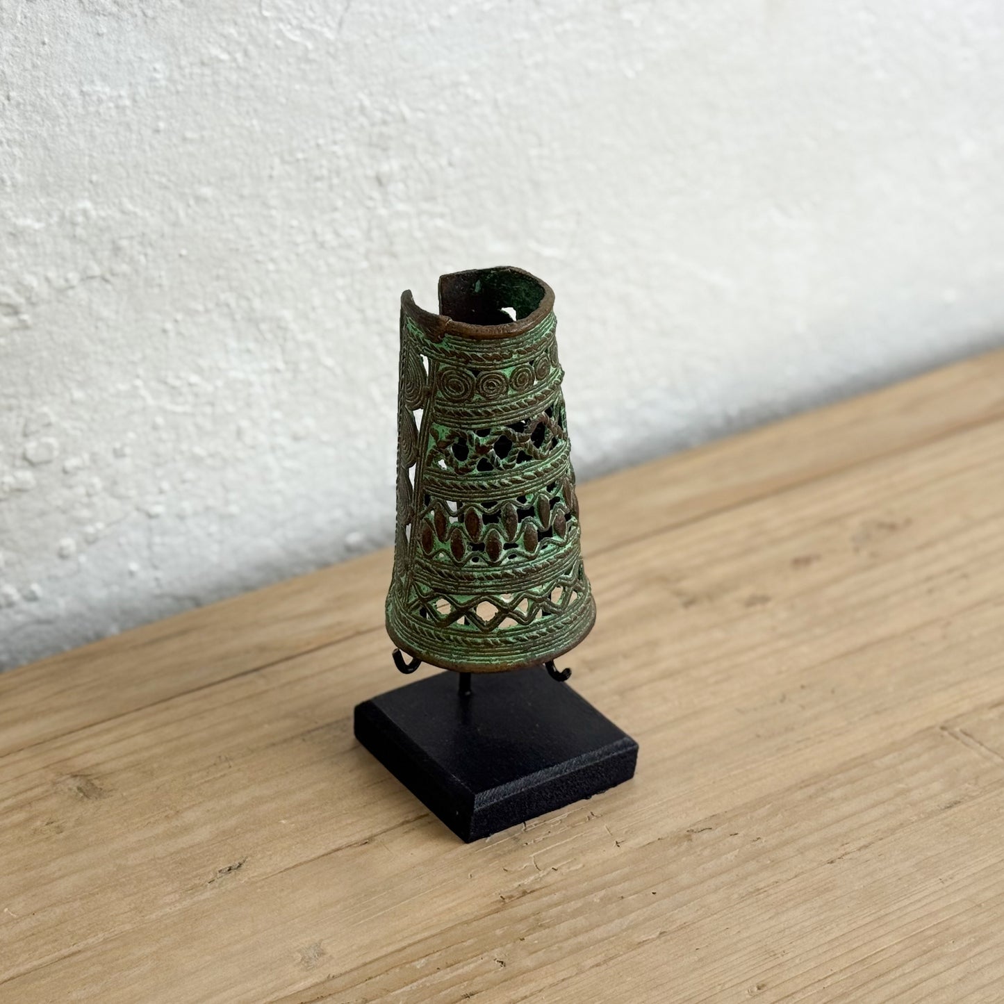 Decorative metal object on a stand against a white wall