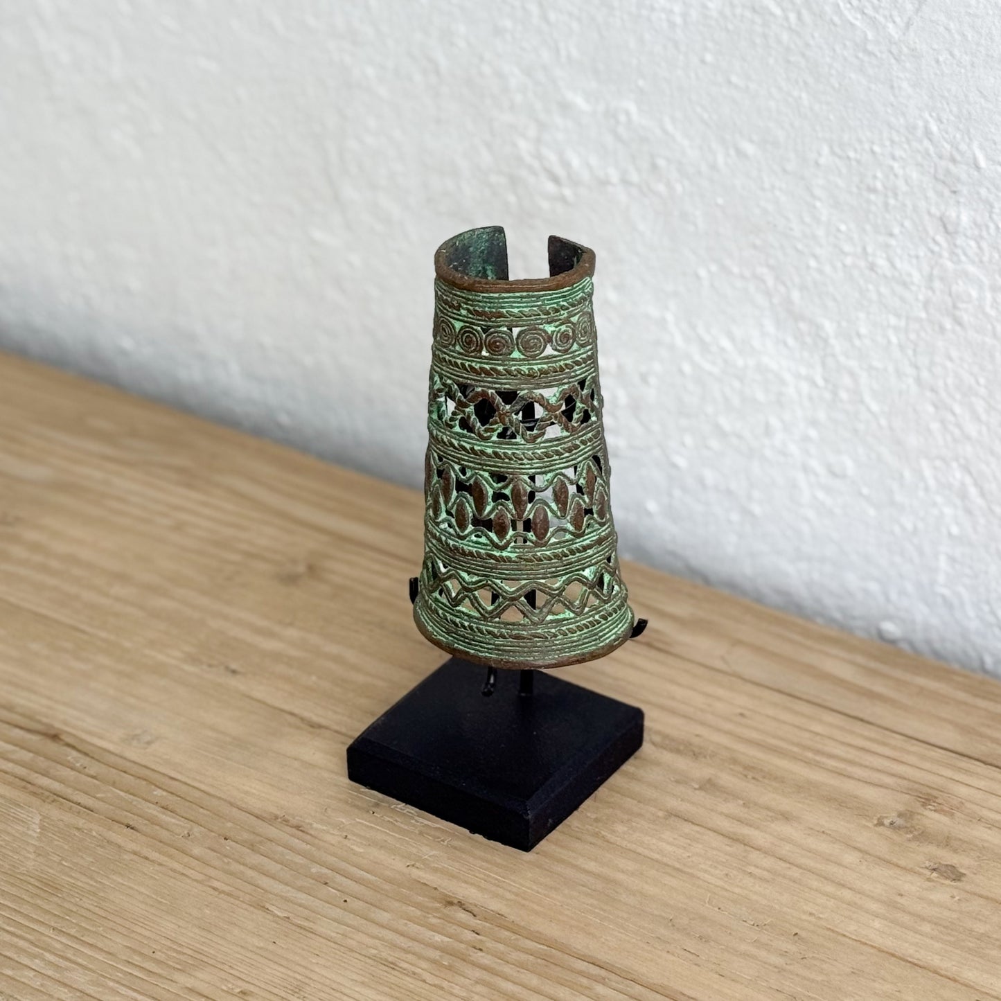 Decorative metal object on a stand against a white wall