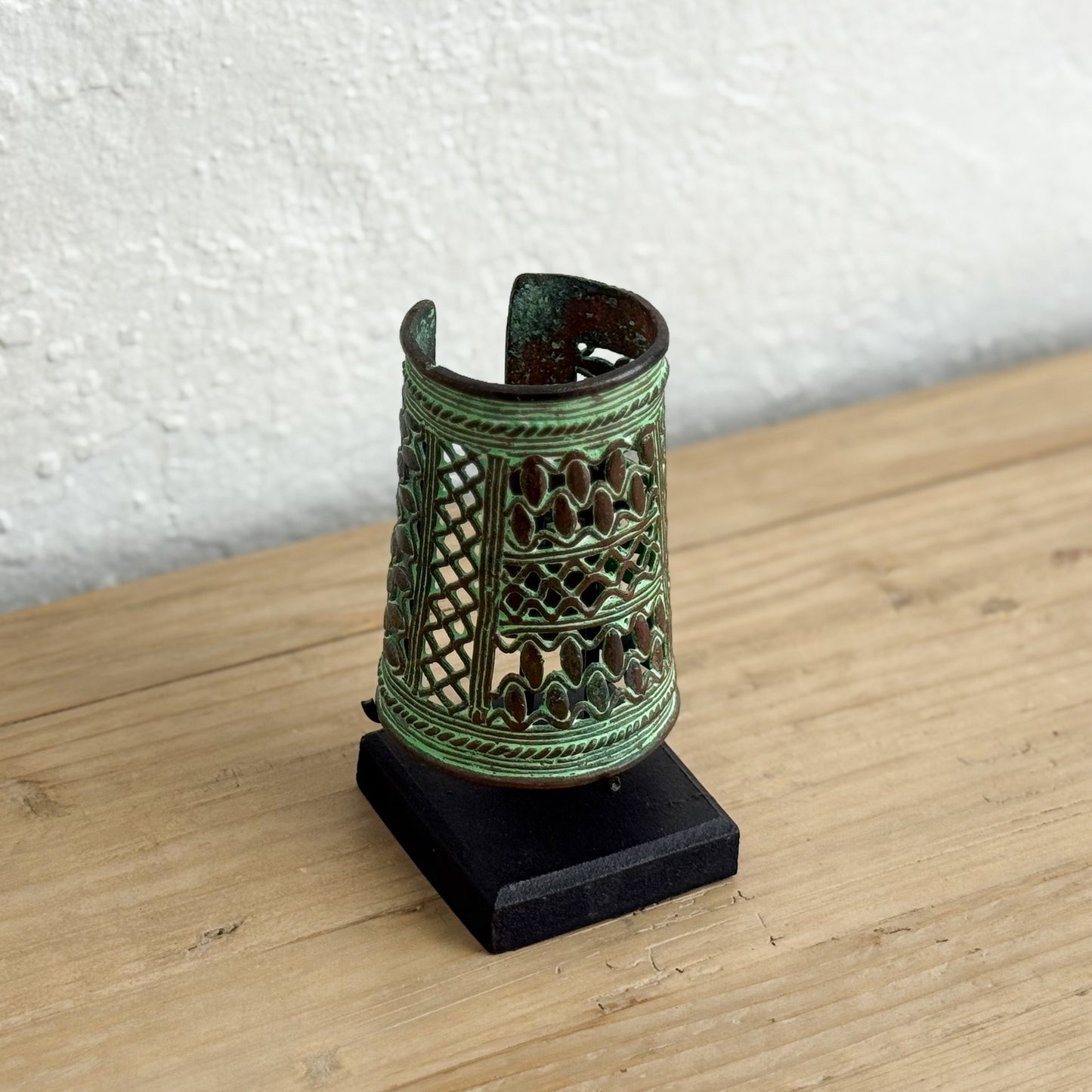Decorative metal object with green patina on a wooden surface