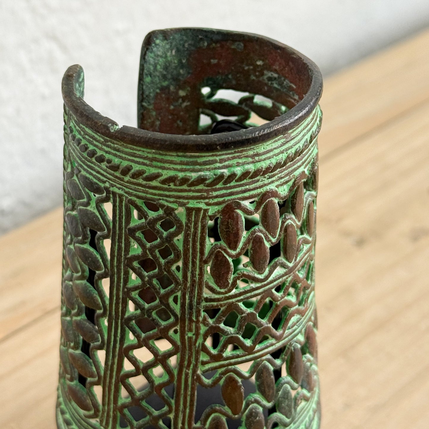 Decorative metal candle holder with intricate patterns on a wooden surface