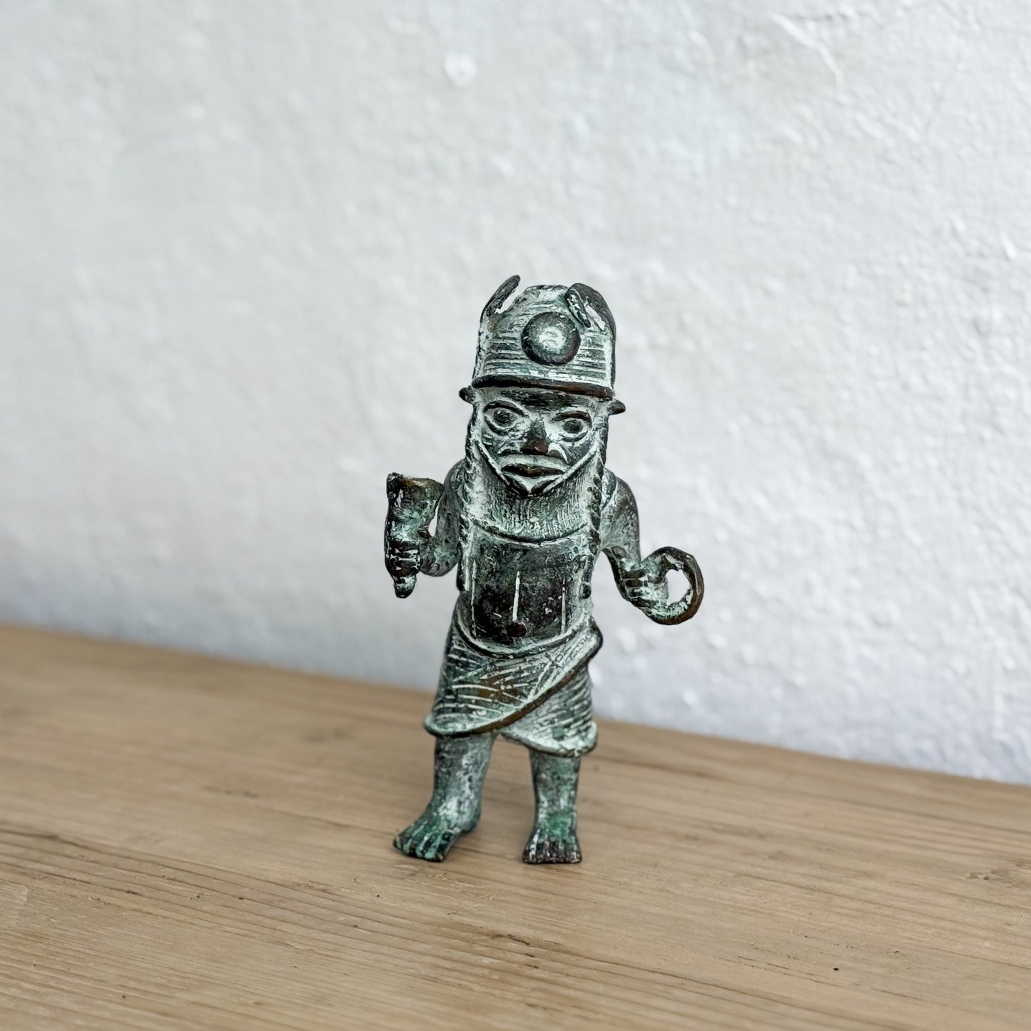 Bronze figurine of a miner on a wooden surface with a white background