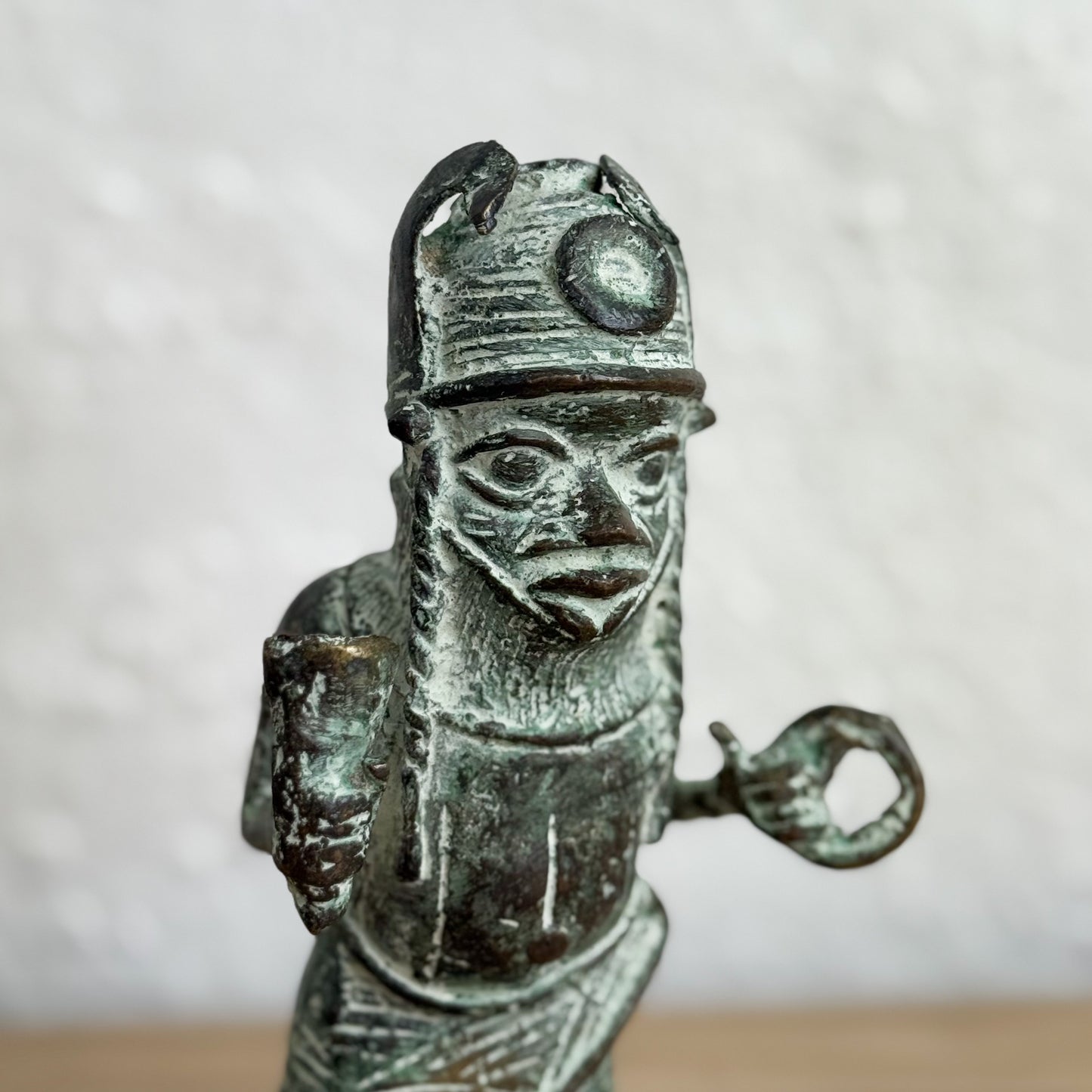 Bronze figurine of a warrior with helmet and spear on a light gray background