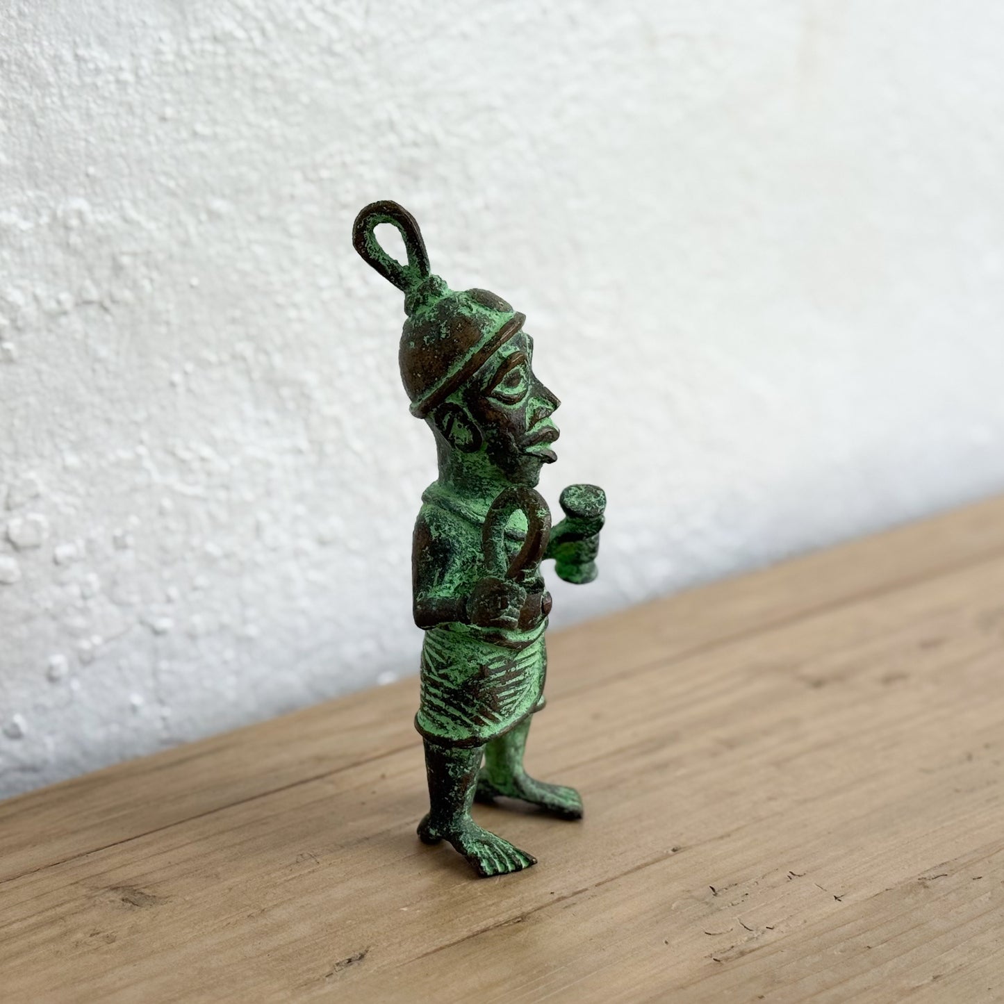 Bronze figurine on a wooden surface with a white textured wall background