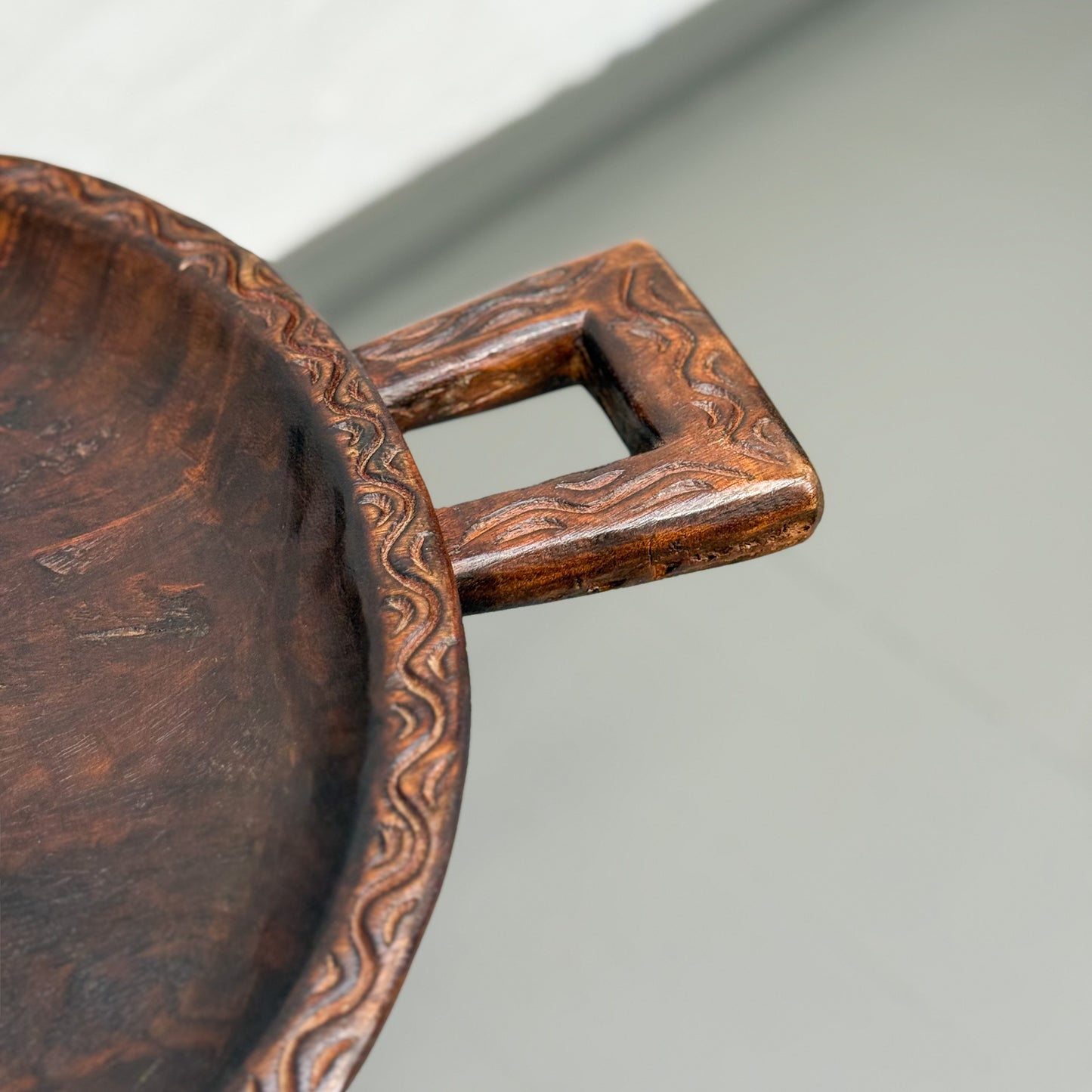 Close-up of a copper bowl with a square handle on a light gray background