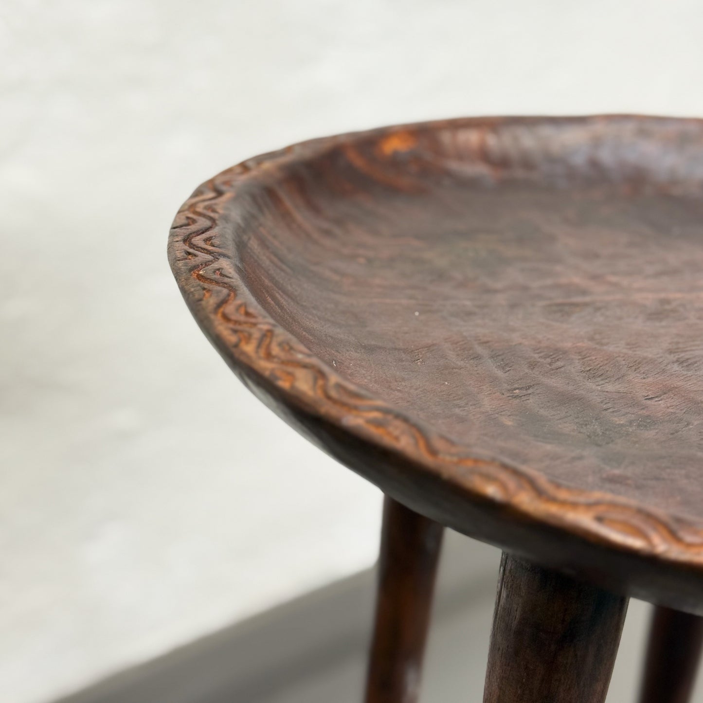 Wooden stool with intricate carvings on a plain background