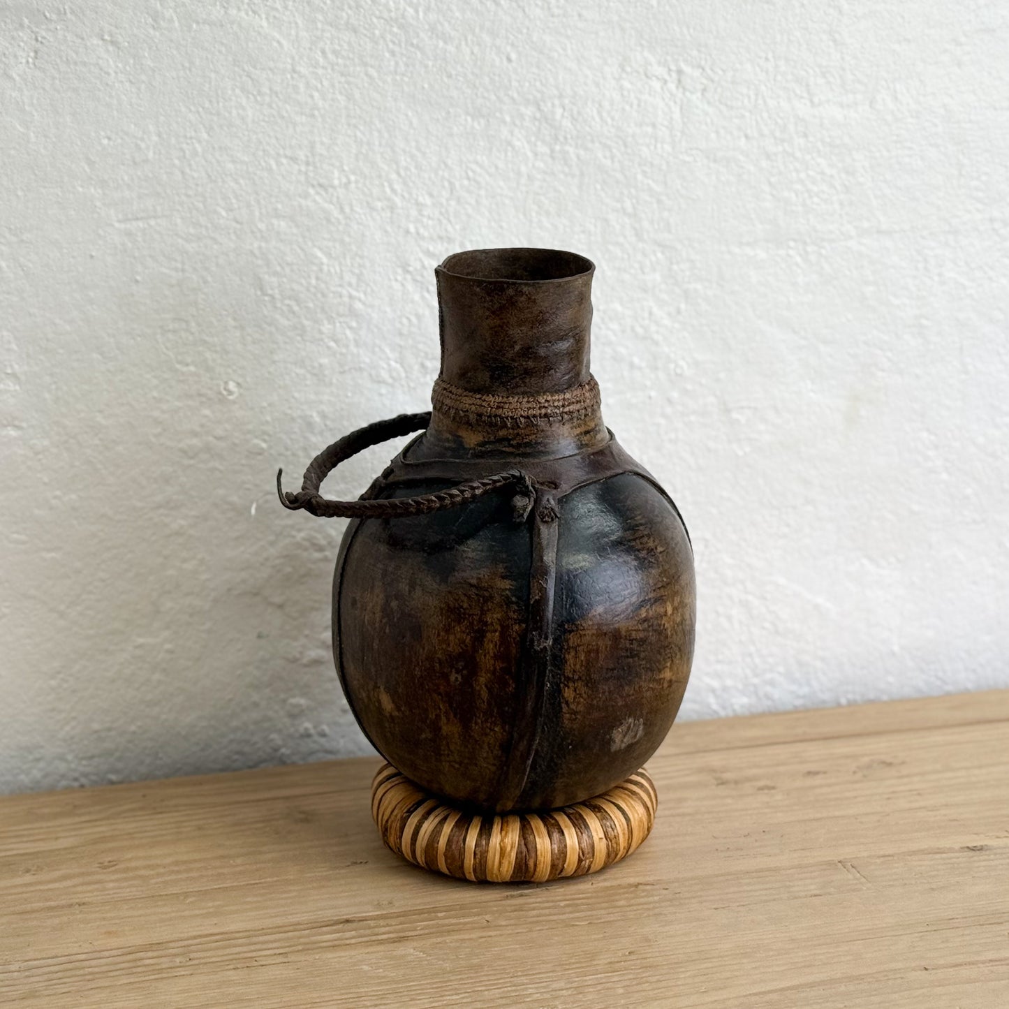Vintage-style metal flask with wooden base on a wooden surface