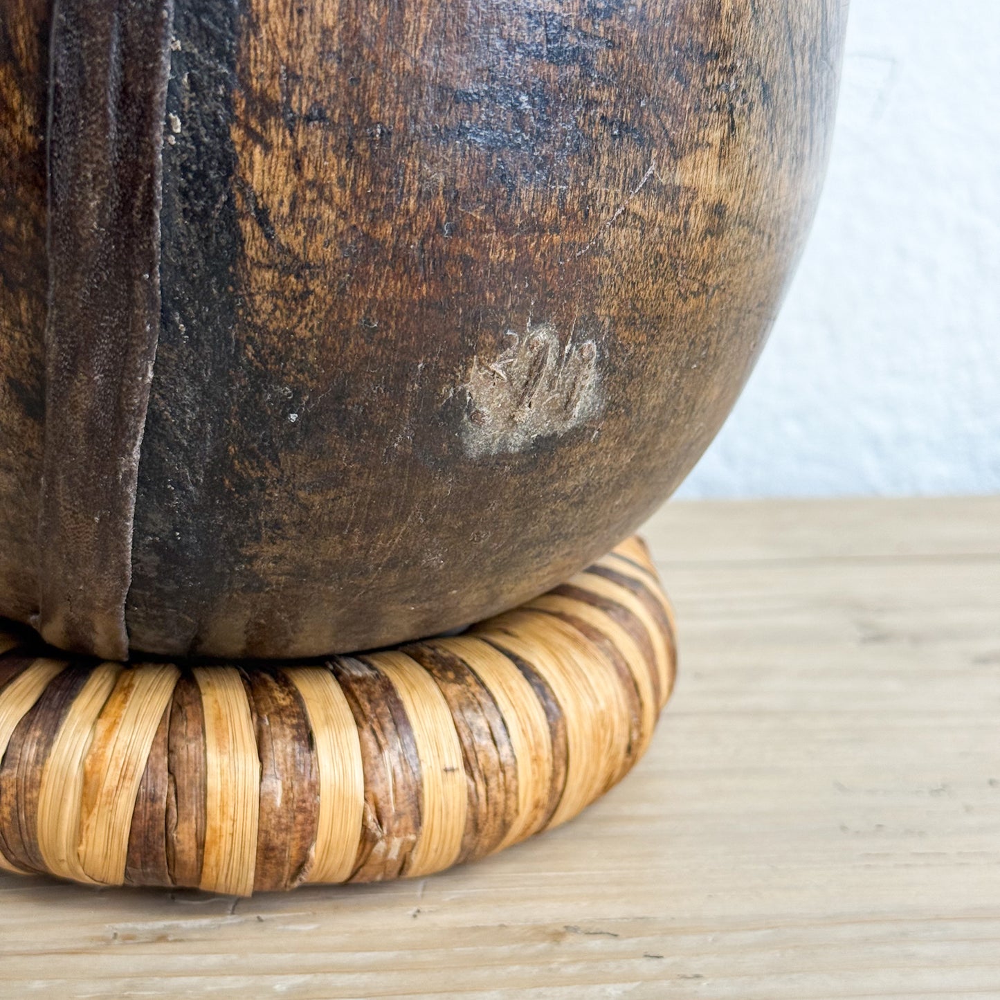 Wooden bowl with woven base on a wooden surface